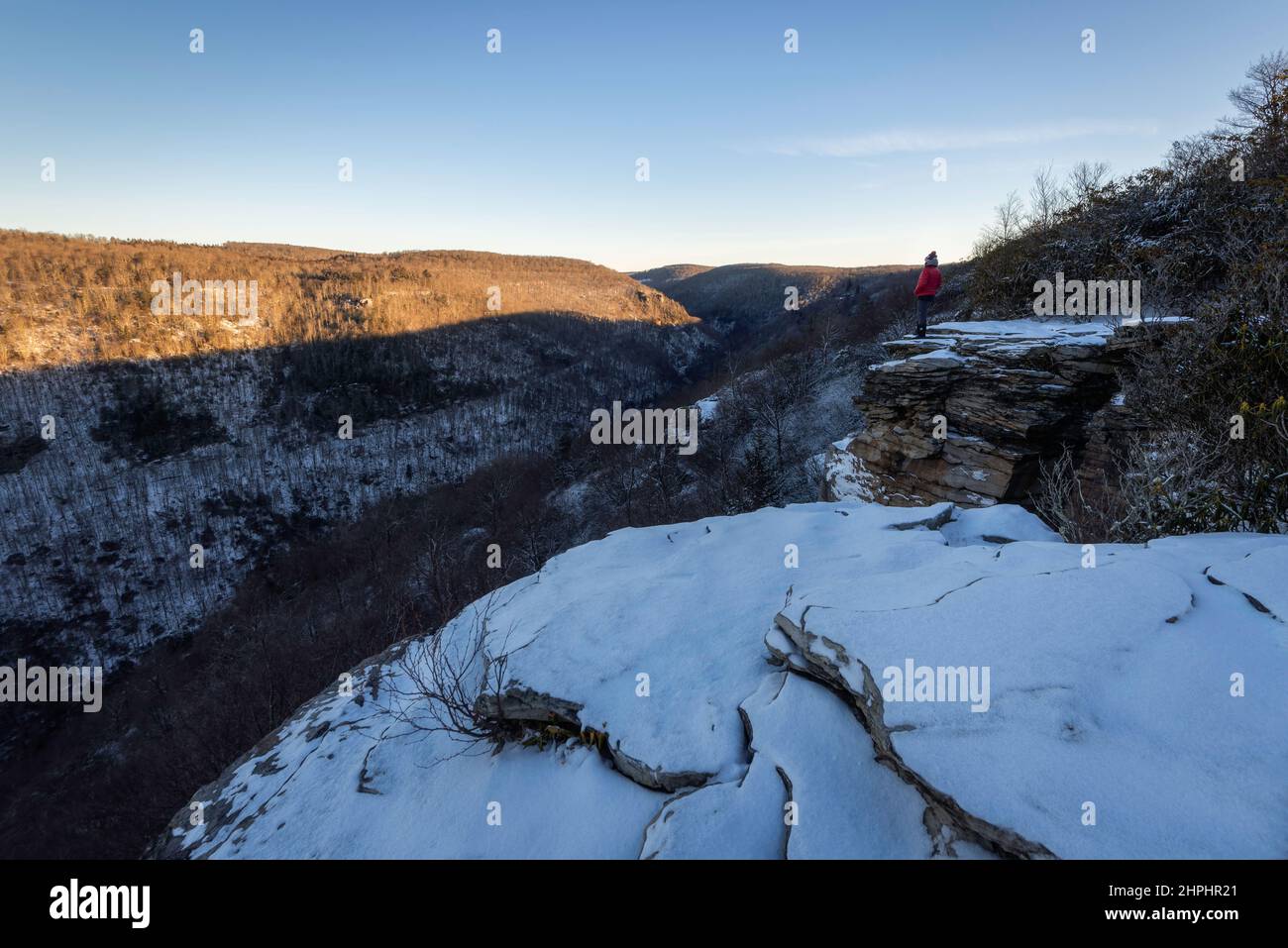 Ein Wanderer am Rande des Blackwater Canyon in West Virginia, wenn das Morgenlicht die Schlucht an einem kalten Wintermorgen füllt. Stockfoto