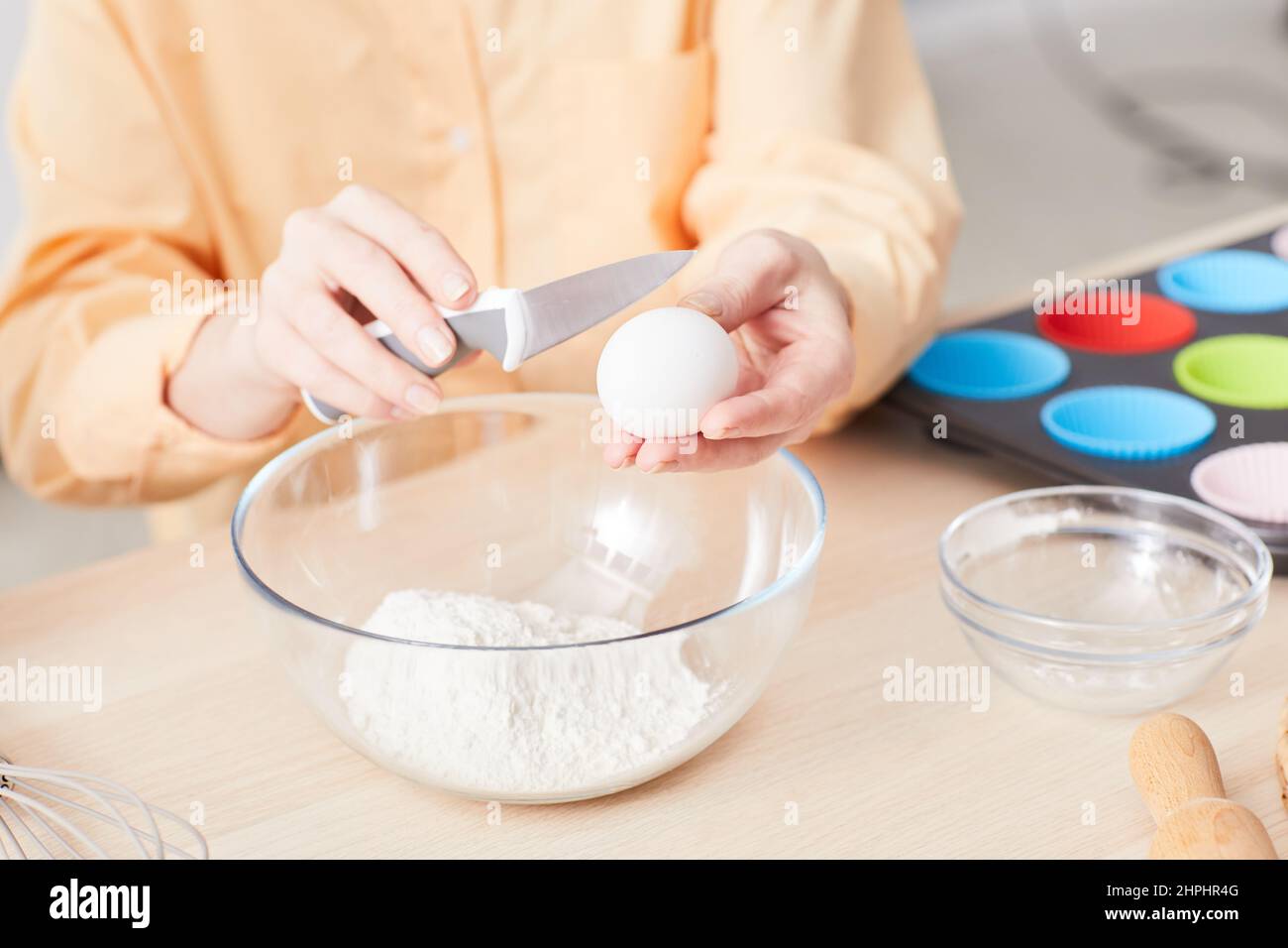 Nahaufnahme einer jungen Frau, die Eier zerbricht, während sie in der Küche hausgemachte Muffins backen, Platz zum Kopieren Stockfoto