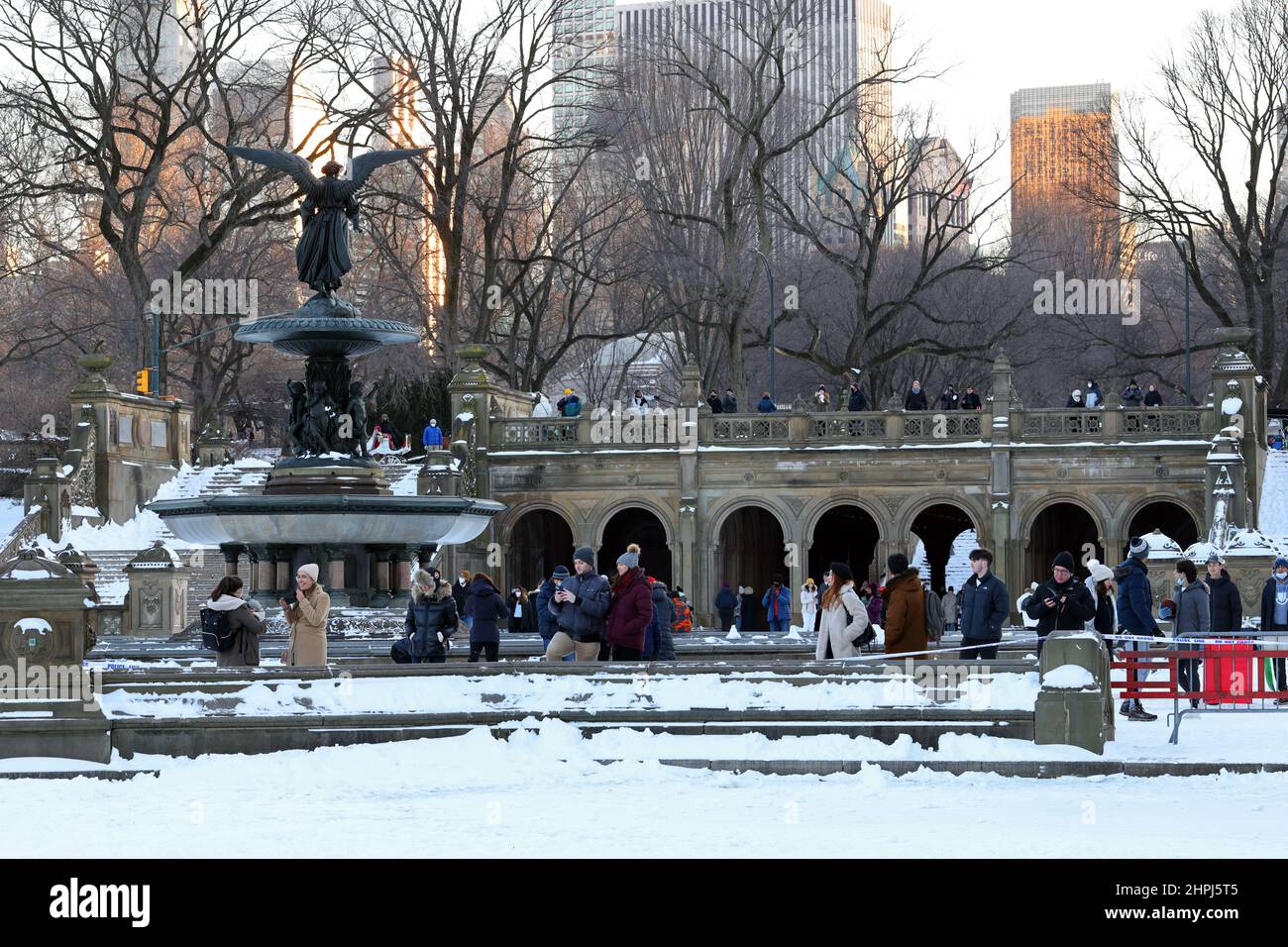 Touristen an einem schneebedeckten Bethesda-Brunnen und einer Terrasse im Winter, die von einem gefrorenen See im Central Park, New York, NY, genommen wurde. Stockfoto
