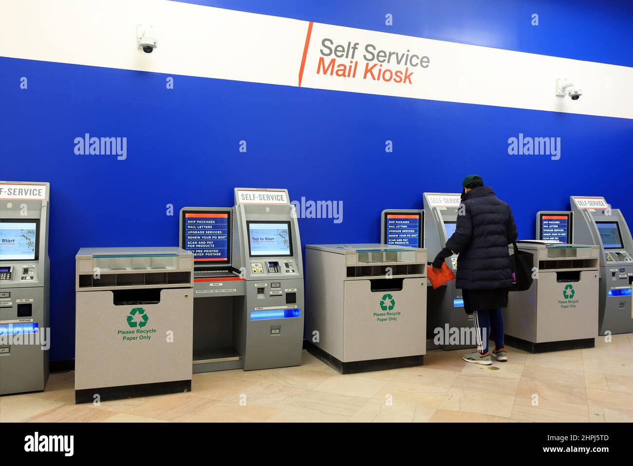 Eine Person verwendet einen Automated Postal Center Self-Service-Kiosk in einem Postamt, um ein Paket zu versenden. Stockfoto