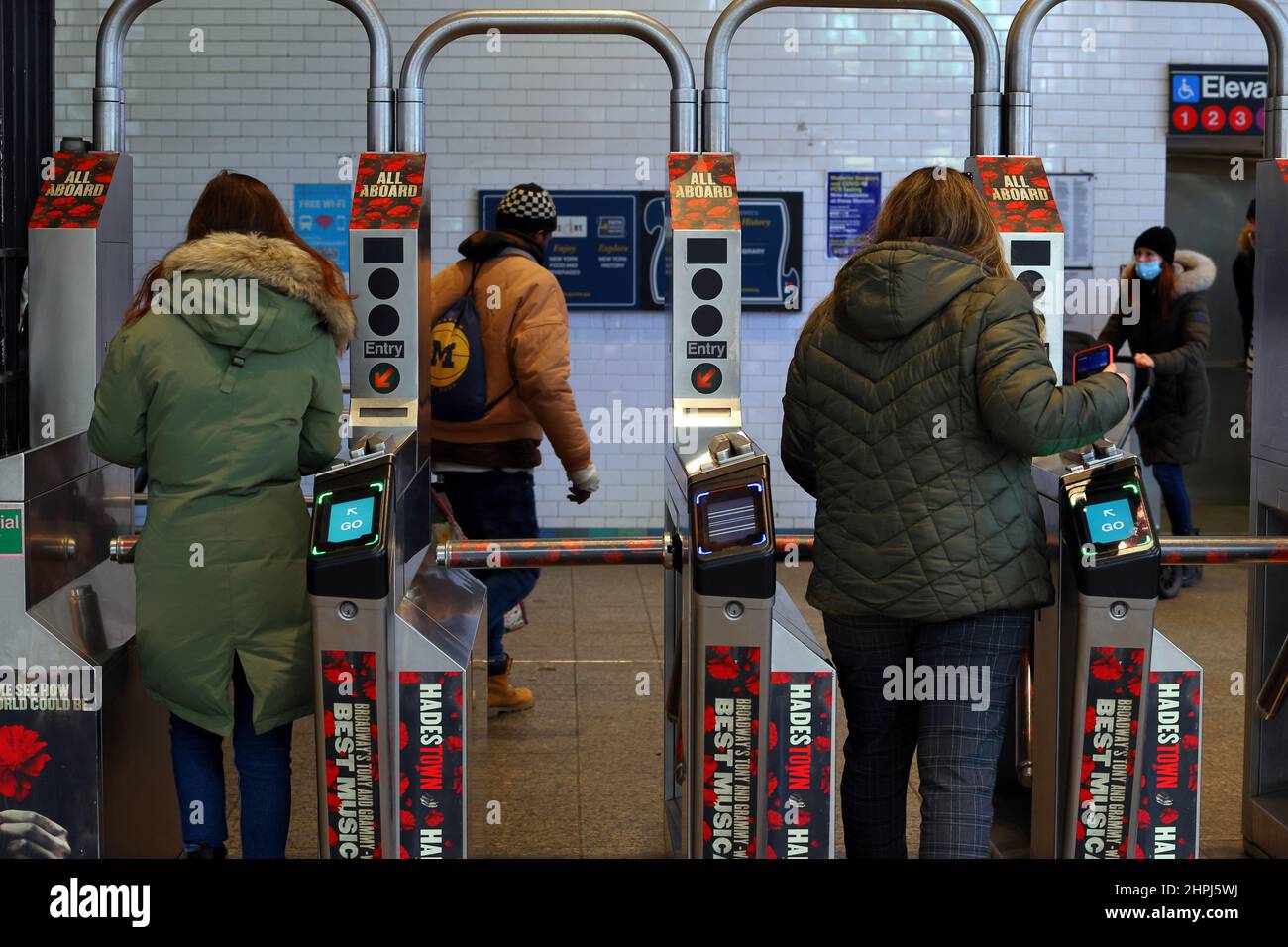 Menschen, die NFC-fähige Smartphones nutzen, um kontaktlose Zahlungsgeräte zu nutzen und durch die Drehkreuze der nyc U-Bahn zu tippen und zu gehen. Stockfoto