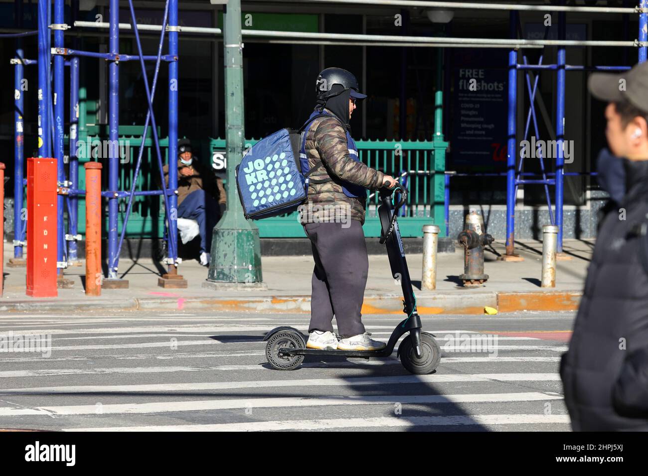 Ein JOKR Lebensmittellieferer auf einem E-Roller, der einen sofortigen Bedarf, schnelle Nachfrage, On-Demand-Lieferung in New York macht. Teil des schnellen Handels Stockfoto