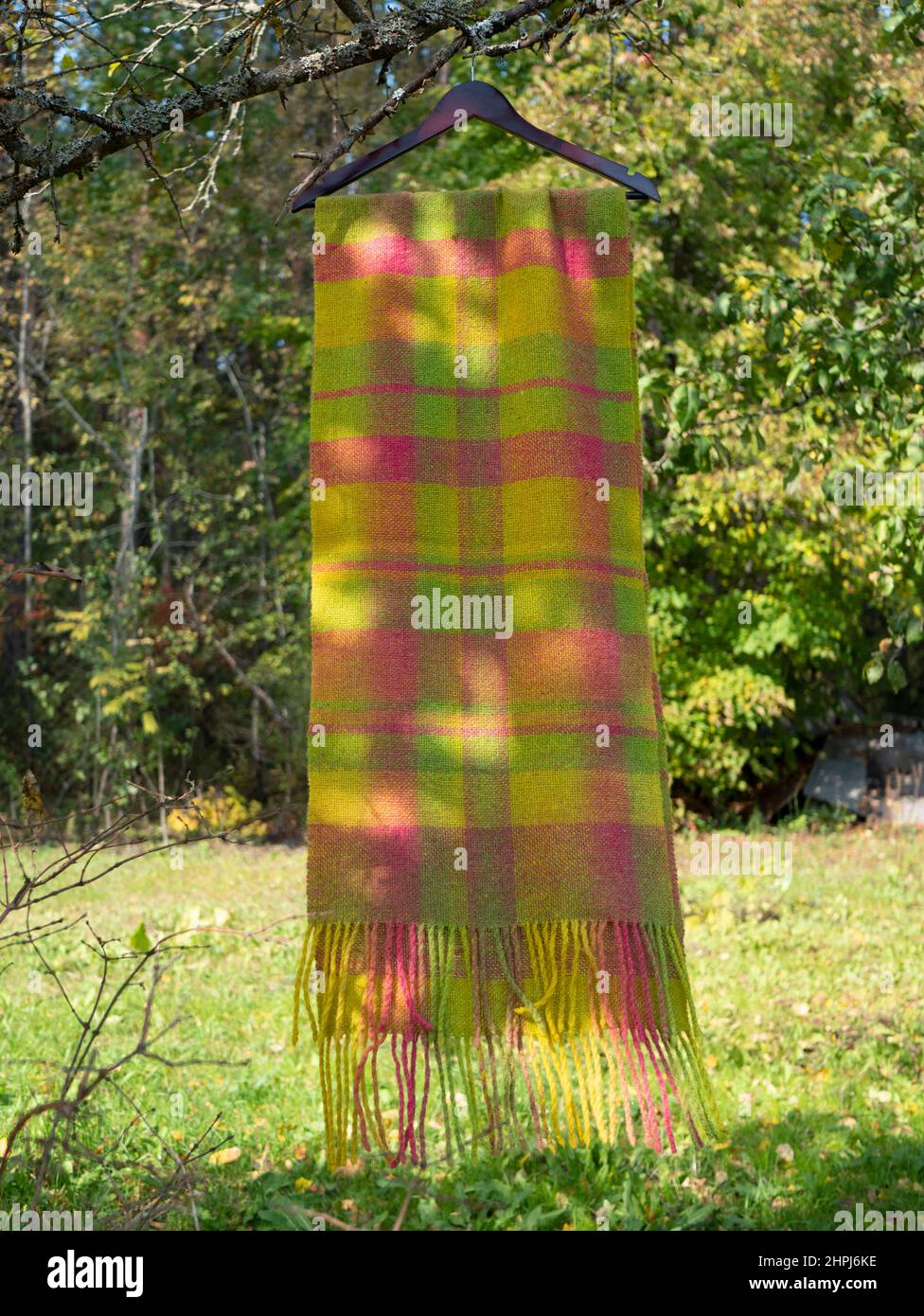 Heller mehrfarbiger Wollschal auf einem Kleiderbügel. Regenbogen Schal im Freien, vertikales Format Stockfoto