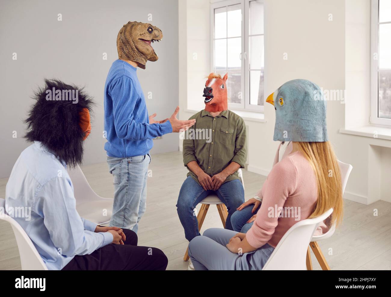 Menschen in lustigen Tiermasken, die während einer Gruppentherapie ein Gespräch führen Stockfoto