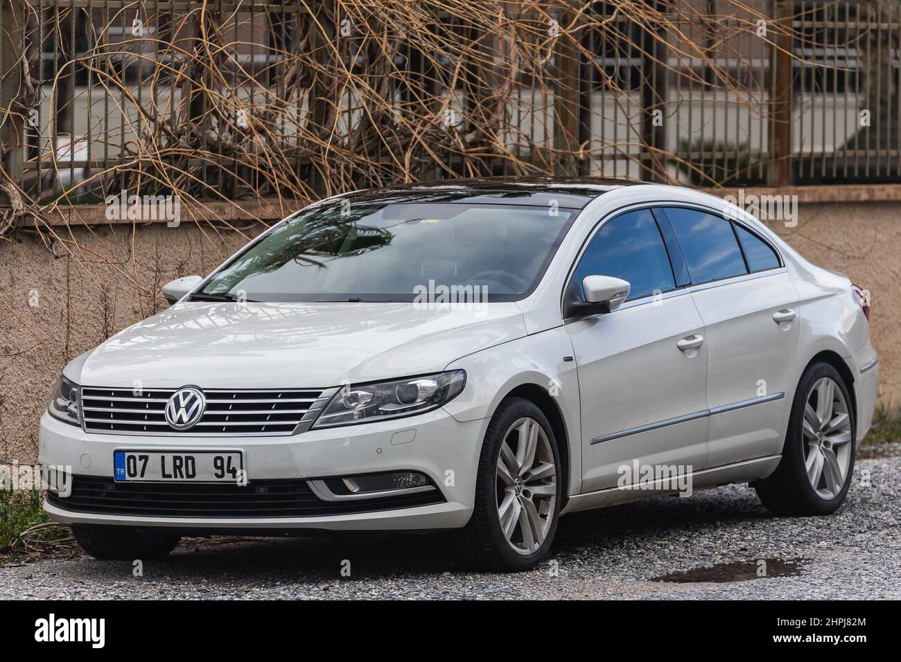 Side, Türkei – 01 2022. Februar: Der weiße Volkswagen Passat cc steht an einem warmen Tag vor dem Hintergrund eines Gebäudes, eines Geschäfts und eines Hotels auf der Straße Stockfoto