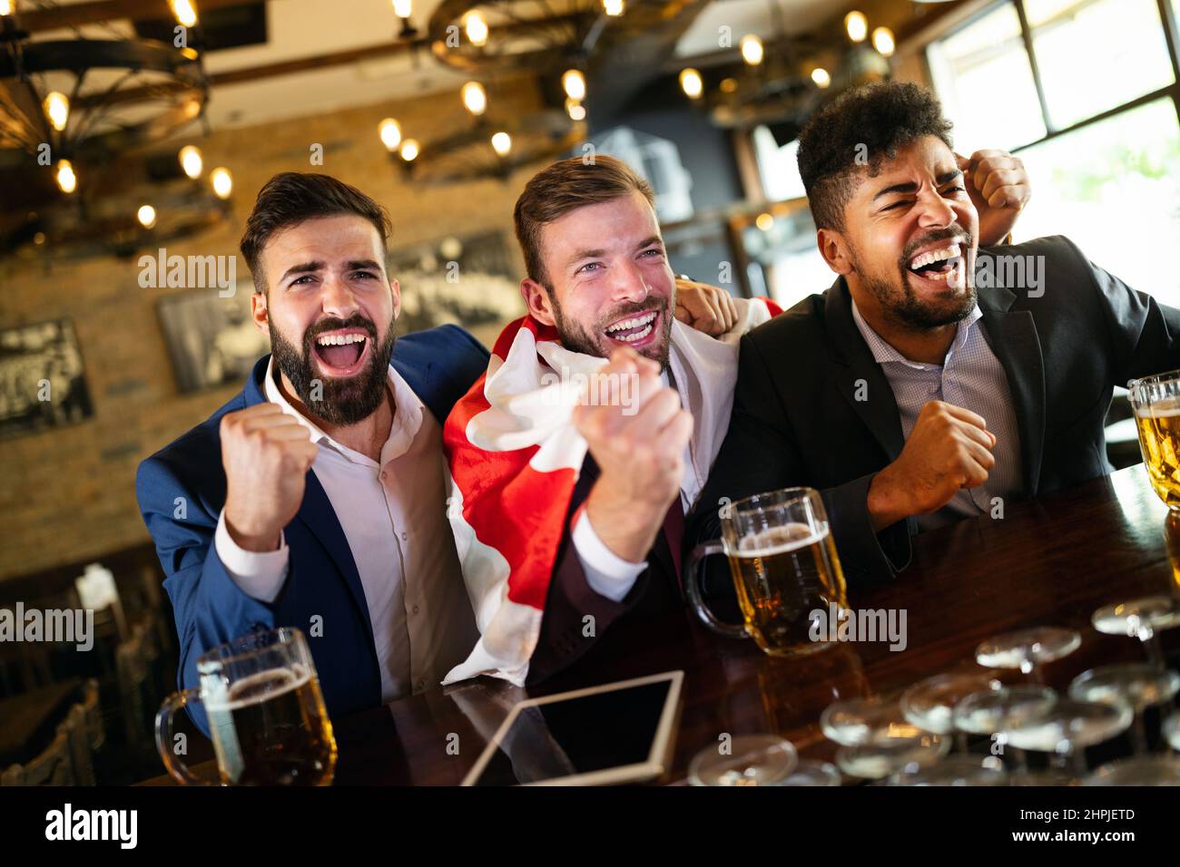 Männerfans schreien und beobachten Fußball im Fernsehen und trinken Bier in einer Kneipe Stockfoto