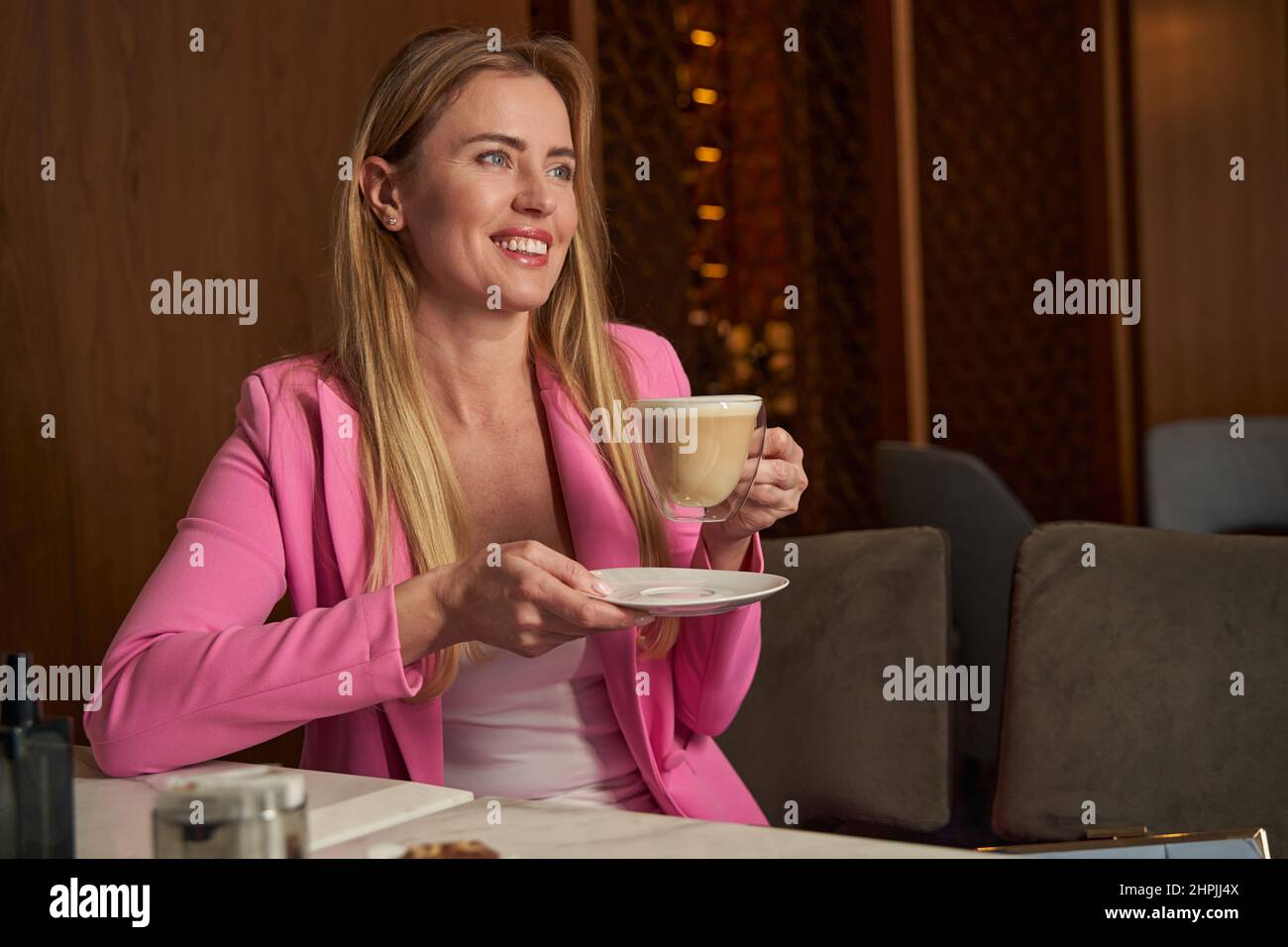 Fröhliche junge Geschäftsfrau, die ihren Kaffee in einem netten Café genießt Stockfoto