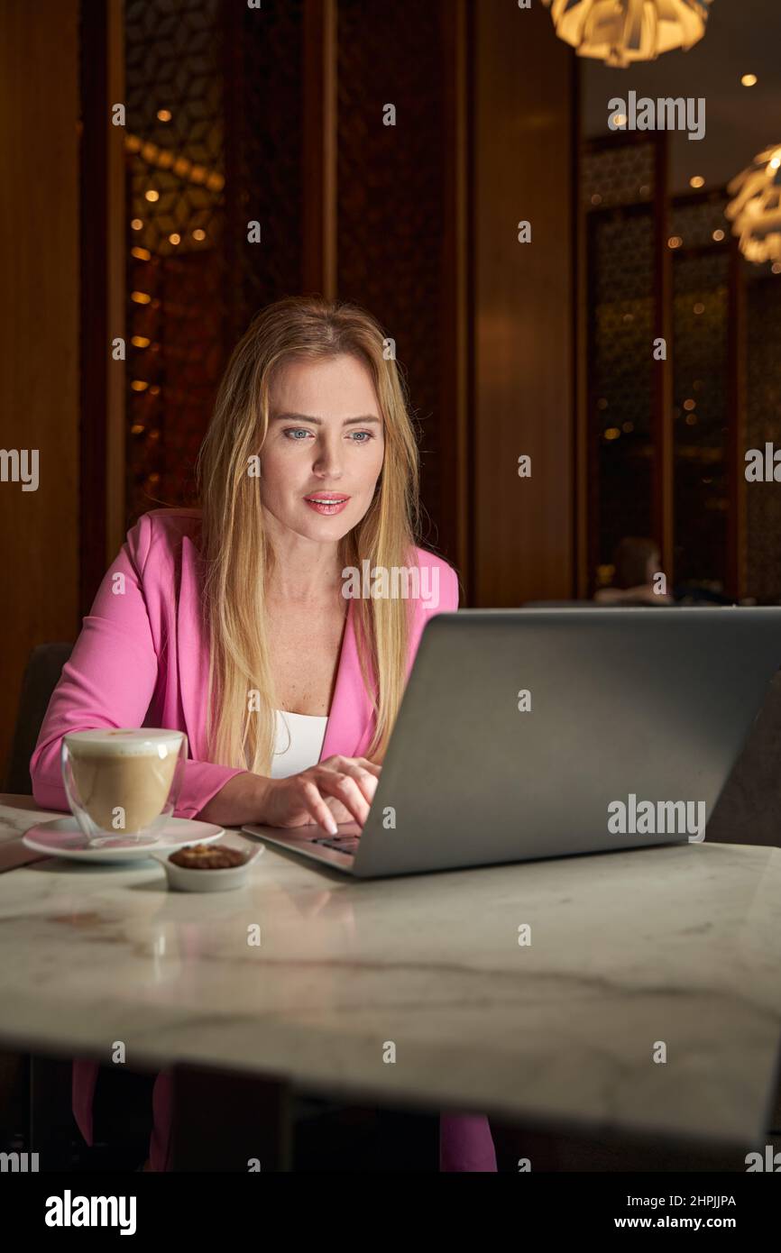 Fokussierte junge Frau, die am Coffee Place am Laptop arbeitet Stockfoto