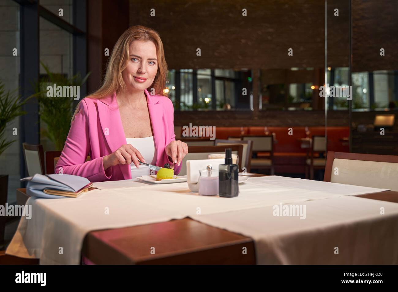 Attraktive junge Frau lächelt und genießt ihr Dessert im Café Stockfoto