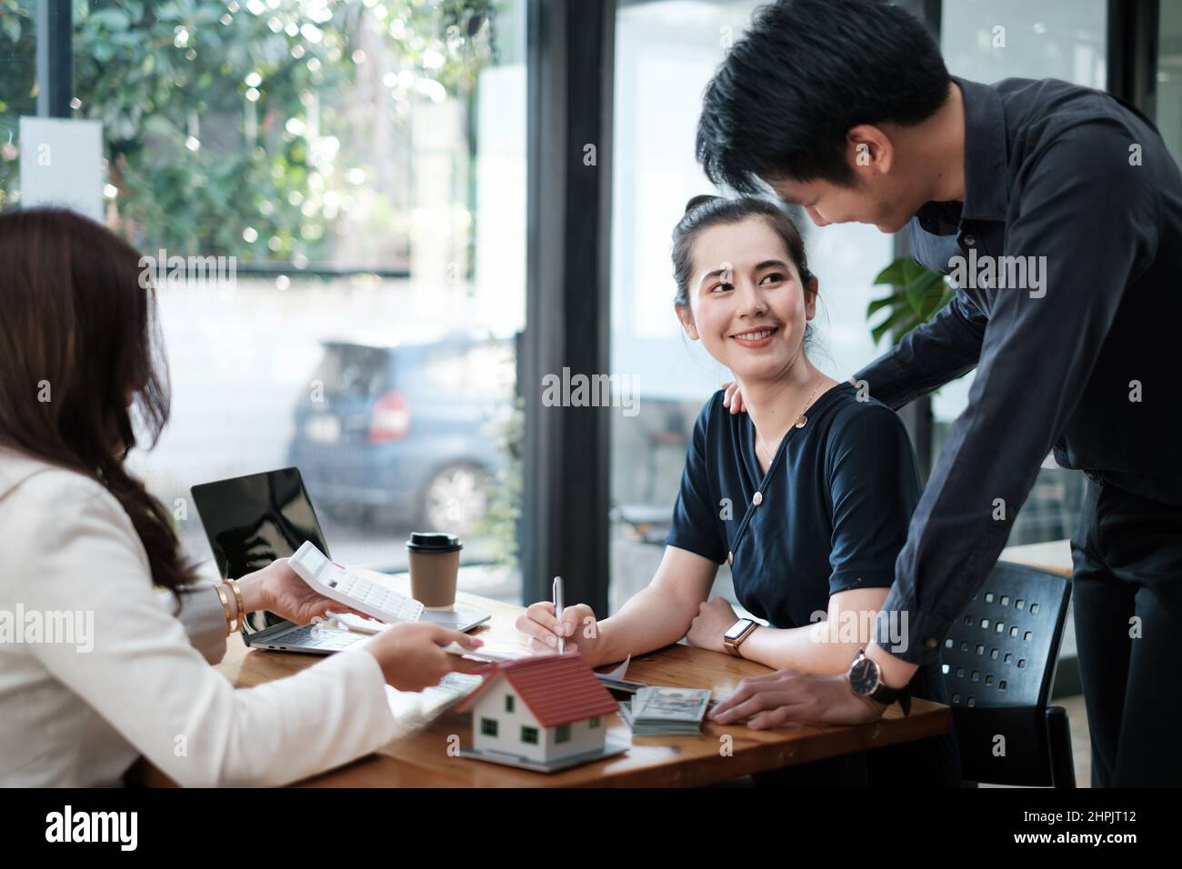 Geschäftsfrau und junges Paar unterzeichnen Vertrag für den Kauf von Haus. Bankmanager und Immobilienkonzept. Stockfoto