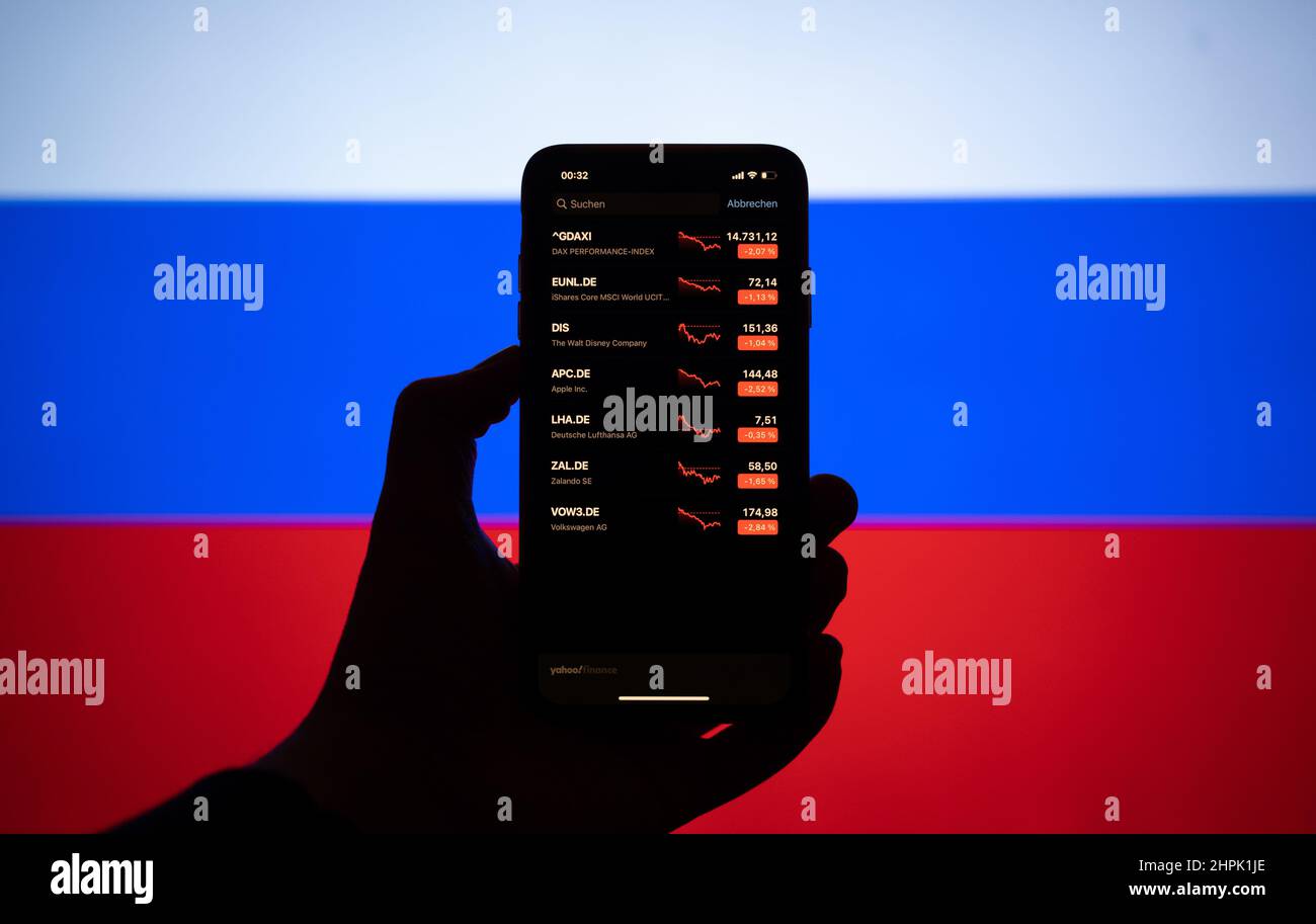 Hamburg, Deutschland. 22nd. Februar 2022. Die Aktienkurse werden auf einem Smartphone vor der russischen Flagge gesehen. Quelle: Daniel Reinhardt/dpa/Alamy Live News Stockfoto