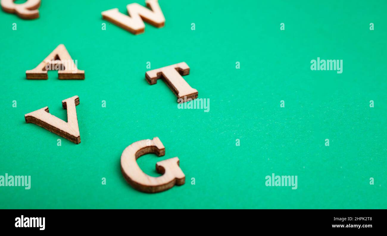 Zufällige Holzbuchstaben isoliert auf grünem Hintergrund Stockfoto