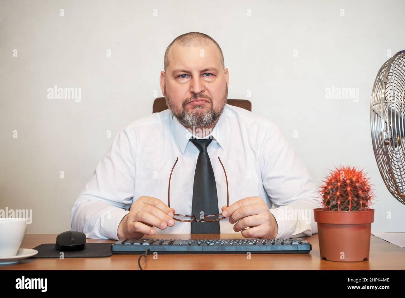 Der Mann stellt komisch die Arbeit eines Geschäftsmannes dar. Er zeigt Unmut im Gesicht und in seiner Haltung. Stockfoto