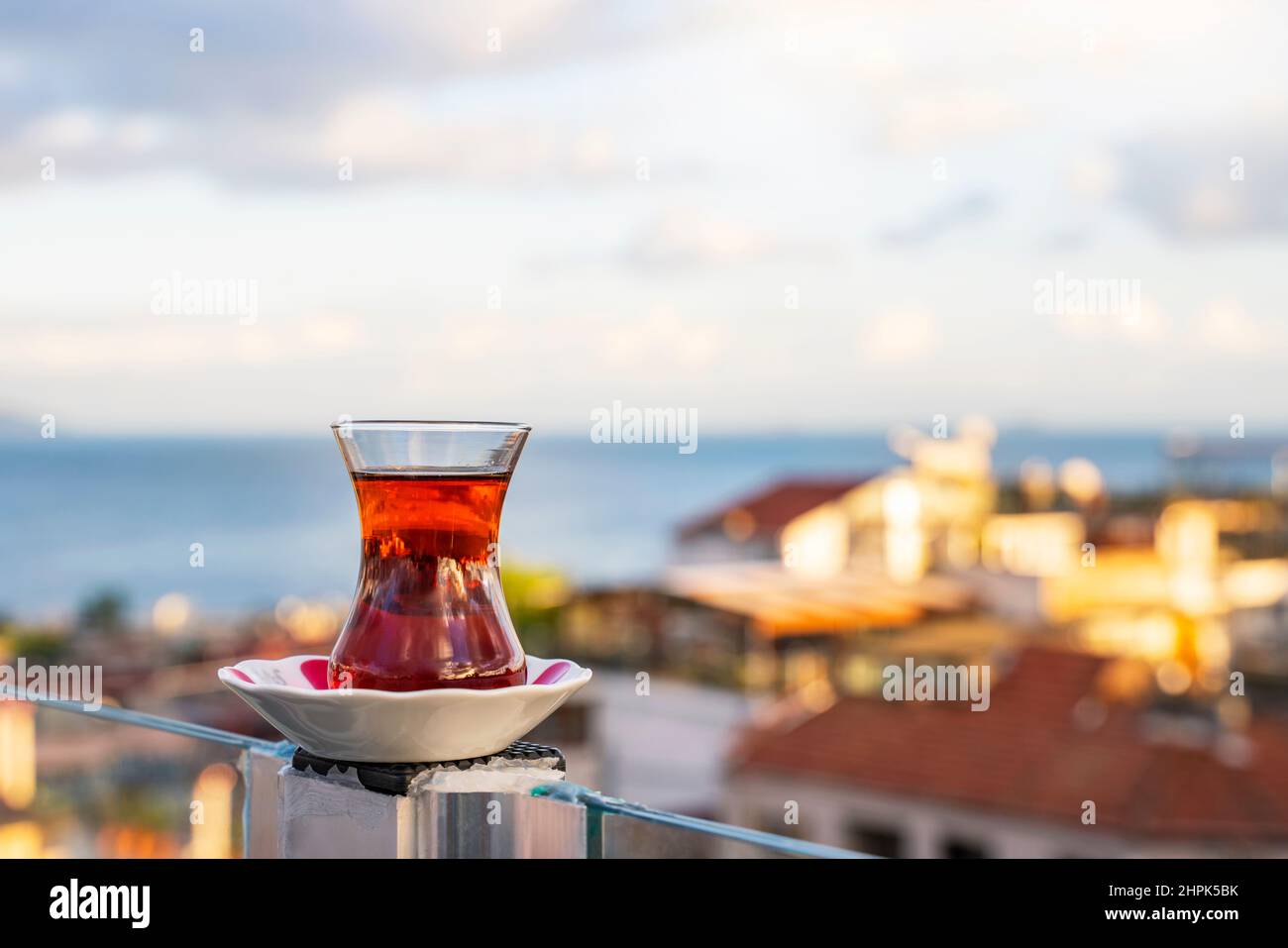Heißer schwarzer türkischer Tee. Eine Tasse türkischer Tee mit einer Untertasse auf dem Hintergrund des Bosporus im Morgengrauen. Stockfoto