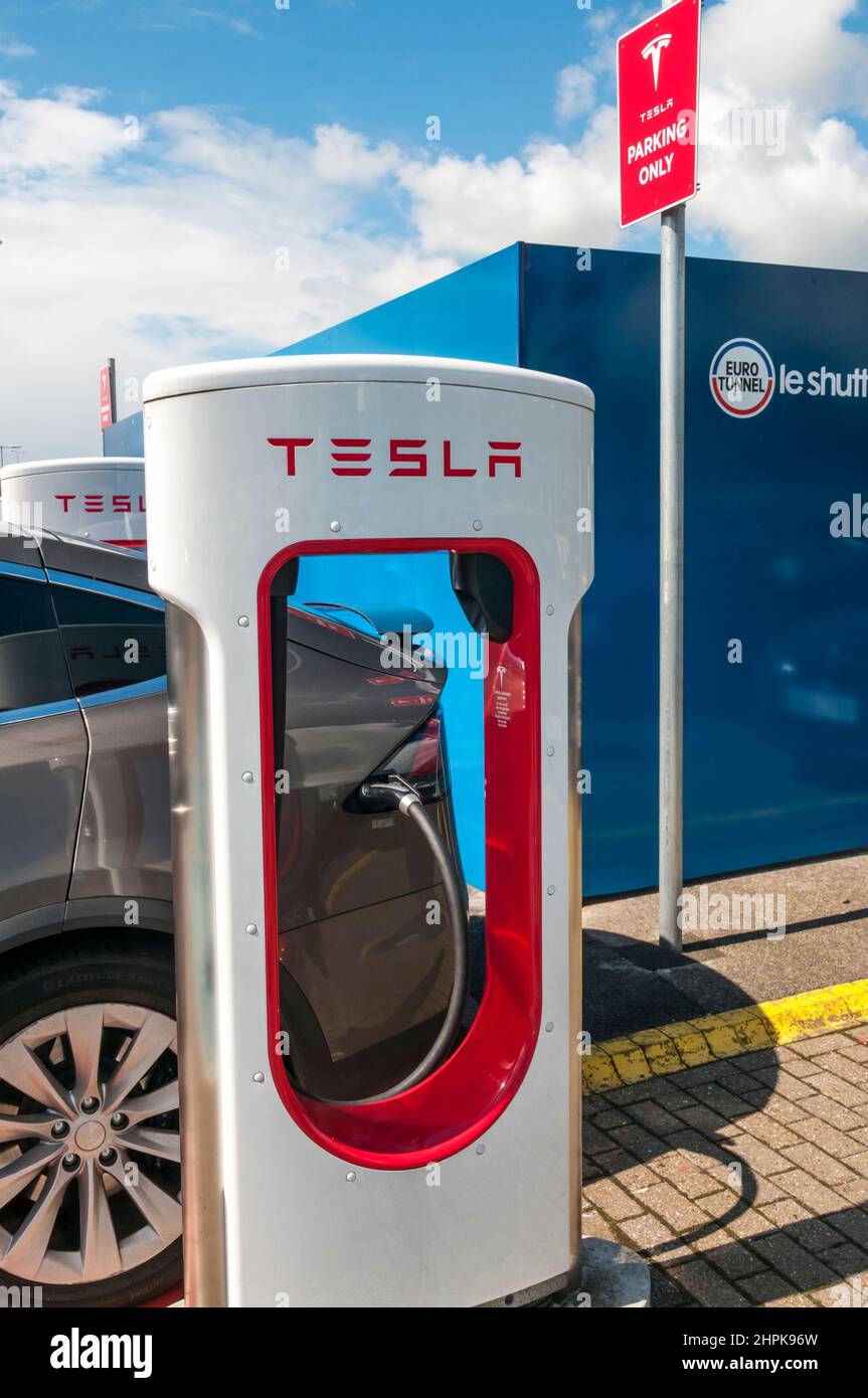 Elektroauto-Wiederaufladung an einer Ladestelle für Tesla-Elektroautos mit Tesla-Namen und -Logo. Stockfoto