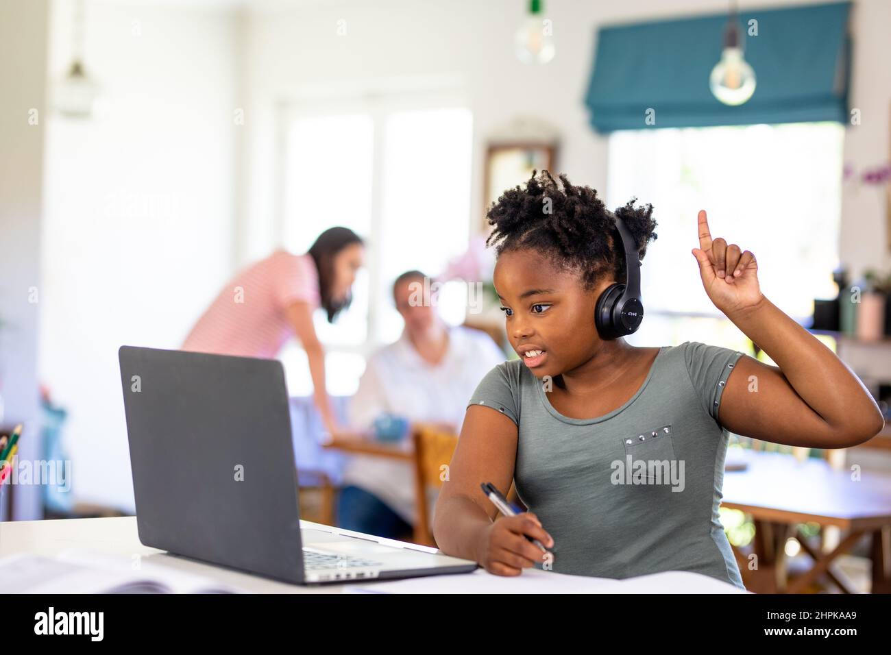 afroamerikanisches Mädchen, das zu Hause die Hand hebt, während es die Online-Schule auf dem Laptop besucht Stockfoto