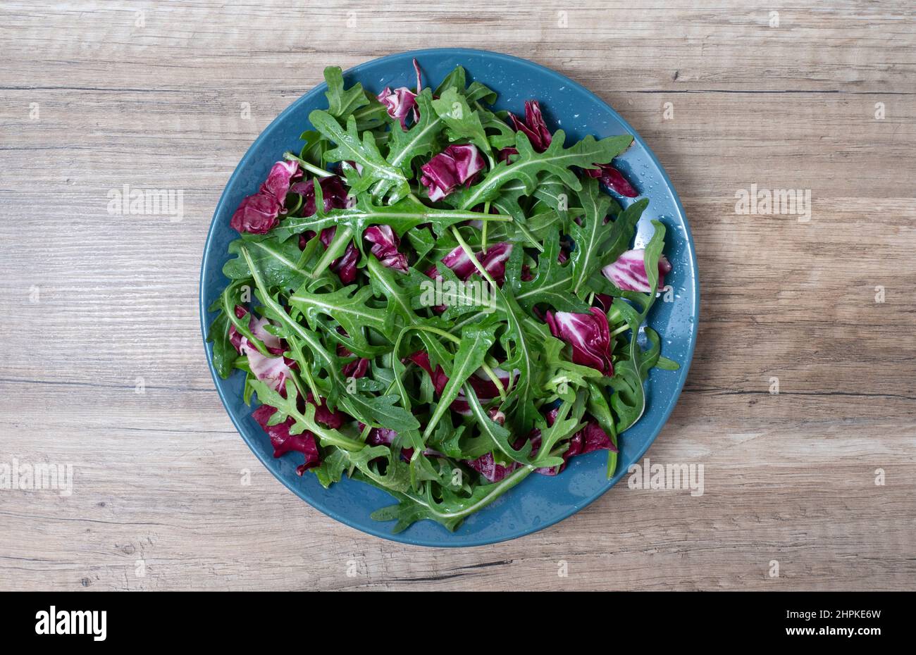 Die Salatblätter vermischen den grünen, saftigen Snack, auf dem Teller auf dem hölzernen Tisch, die gesunde Mahlzeit. Stockfoto