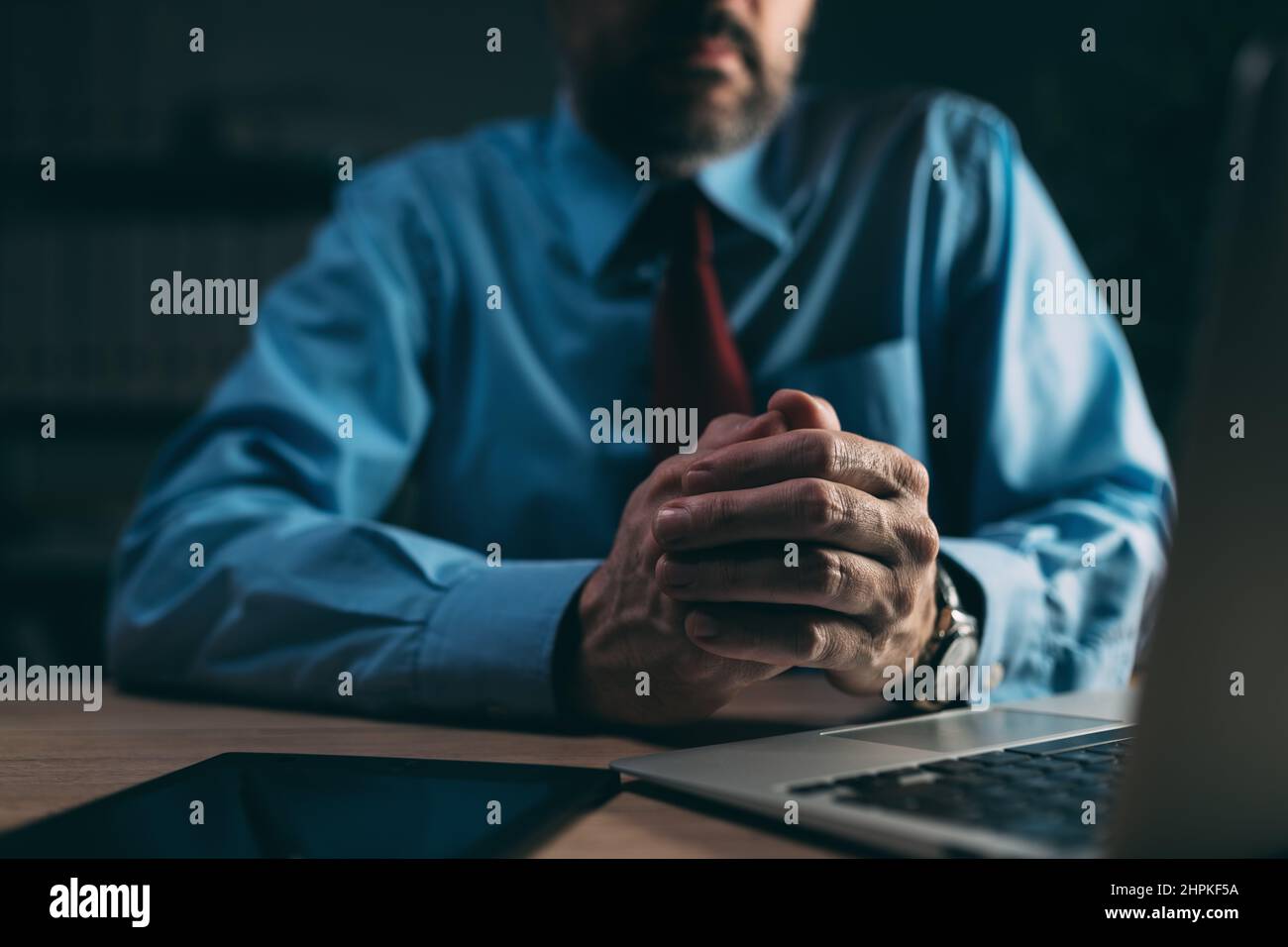 Geschäftsmann reibt sich die Hände als Körpersprache Zeichen der Angst in dunklen Büroinnenraum, selektiver Fokus Stockfoto