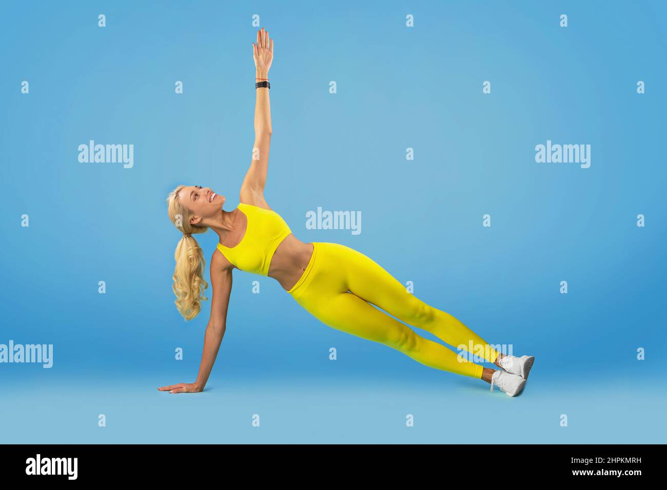 Lächelnde Junge Frau Tut Side Plank Balance Übung Stockfoto