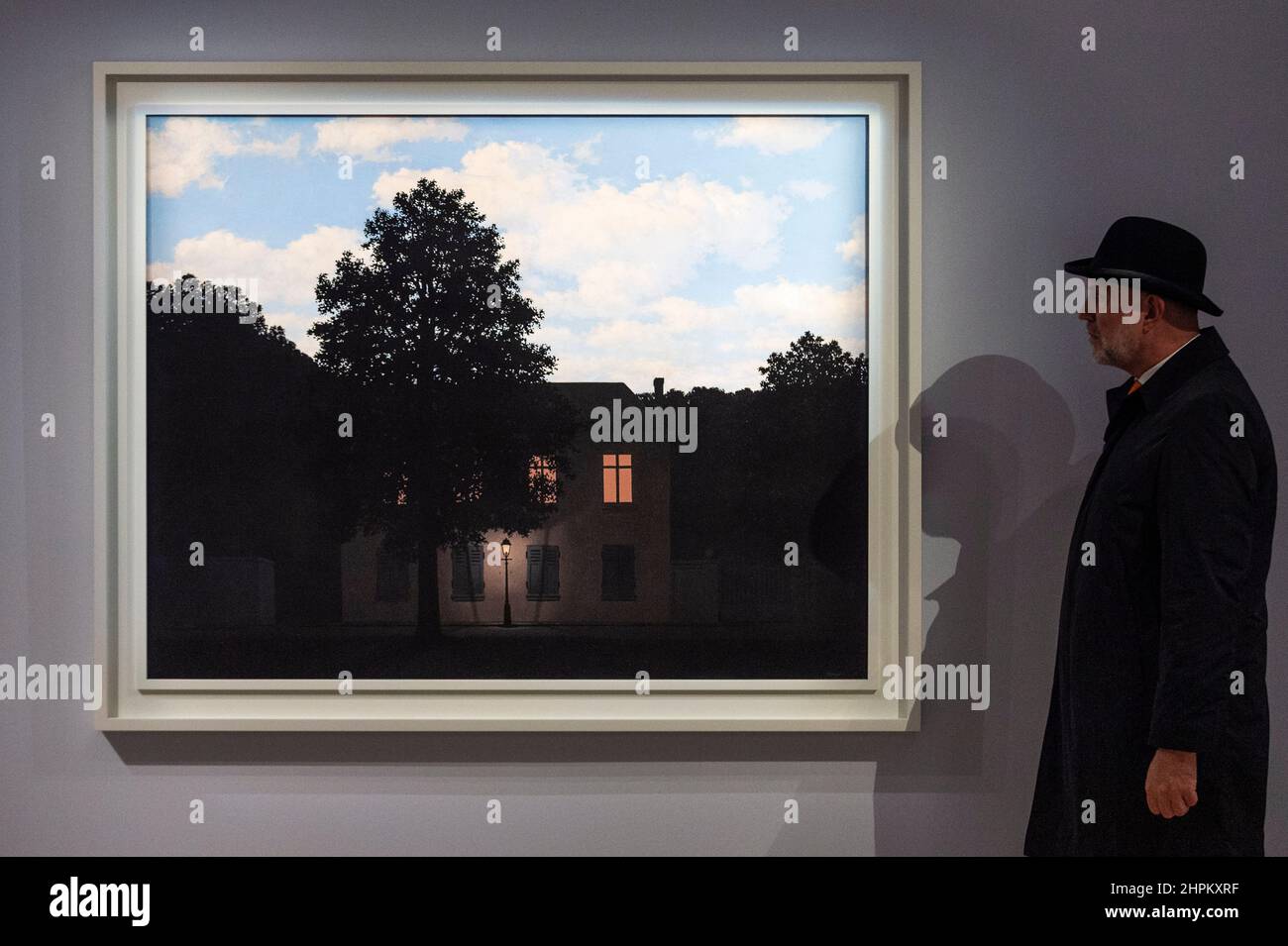 London, Großbritannien. 22nd. Februar 2022. Ein Mitarbeiter posiert mit „L'Empire des Lumières“, 1961, von René Magritte, (mit mehr als £45 Millionen Einwohnern) bei einer Vorschau auf Sothebys bevorstehenden Verkauf moderner und zeitgenössischer Kunst. Die Werke werden am 2. März in Sothebys New Bond Street Galerien versteigert. Kredit: Stephen Chung/Alamy Live Nachrichten Stockfoto