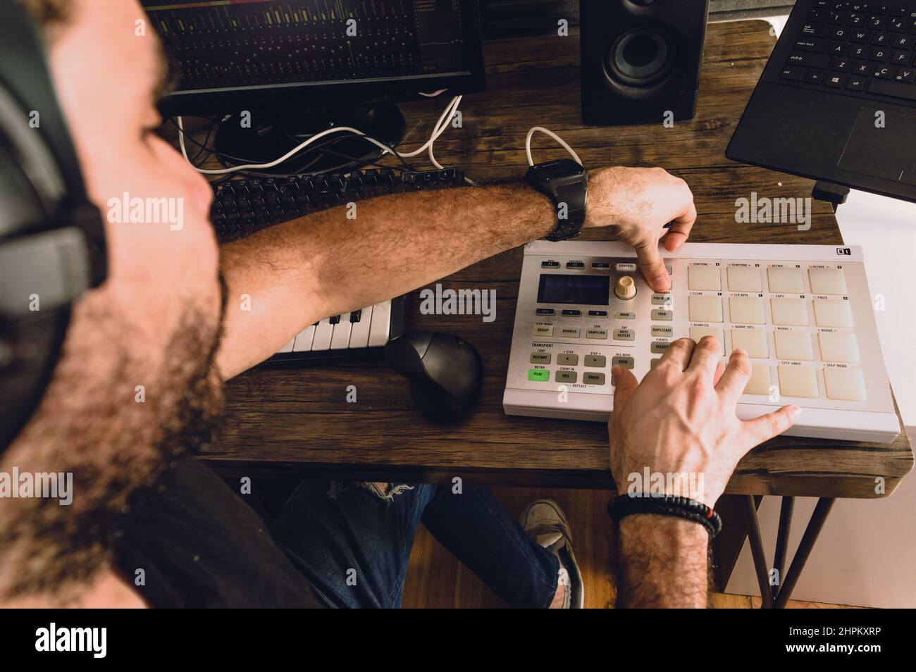 Aus erster Person betrachtet, wie der kaukasische Mann in seinem Heimstudio Musik kreist und Beats mit Midi-Controller, Keyboards, Computer und Notebook produziert, Musik Stockfoto