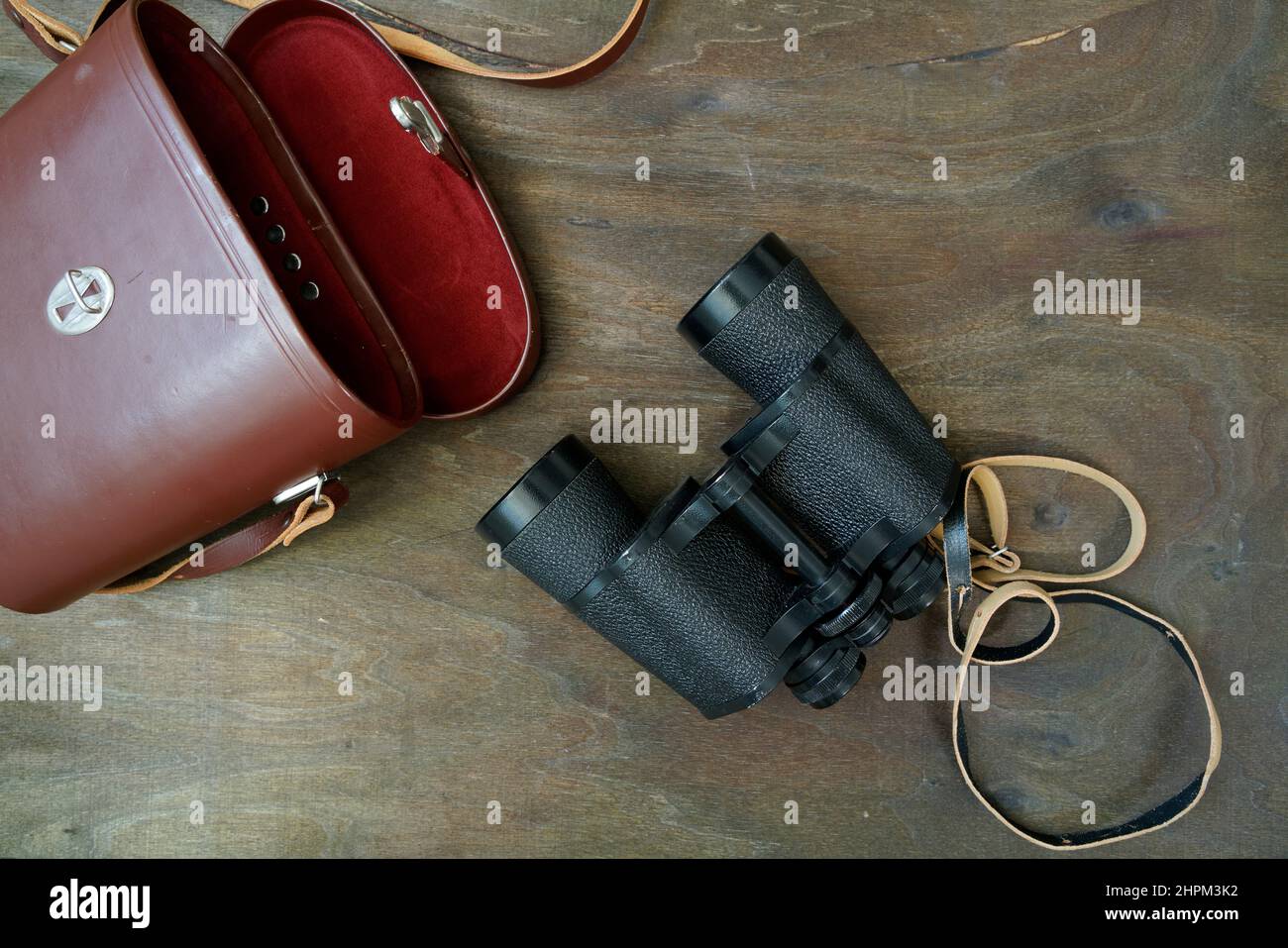 Altes deutsches Fernglas mit Lederetui auf dunklem Holzsockel, flach liegend Stockfoto