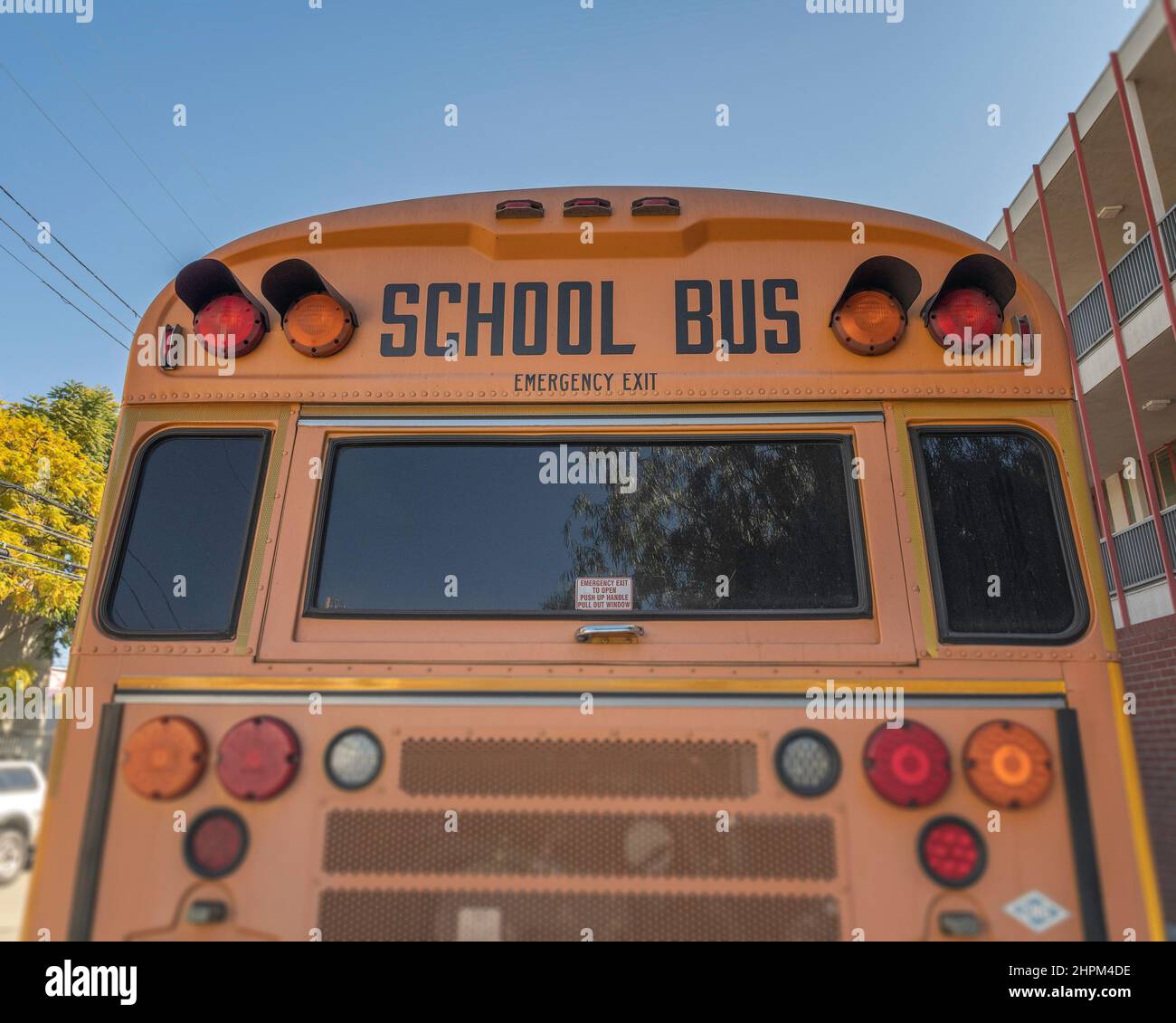 Die Rückseite eines Schulbusses vor einer Grundschule. Stockfoto