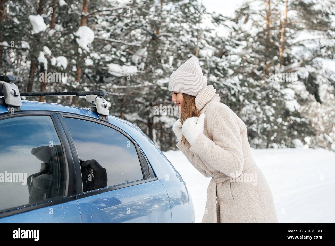 Mädchen im Winterwald gibt vor, im Fenster des Autos reflektiert zu werden Stockfoto