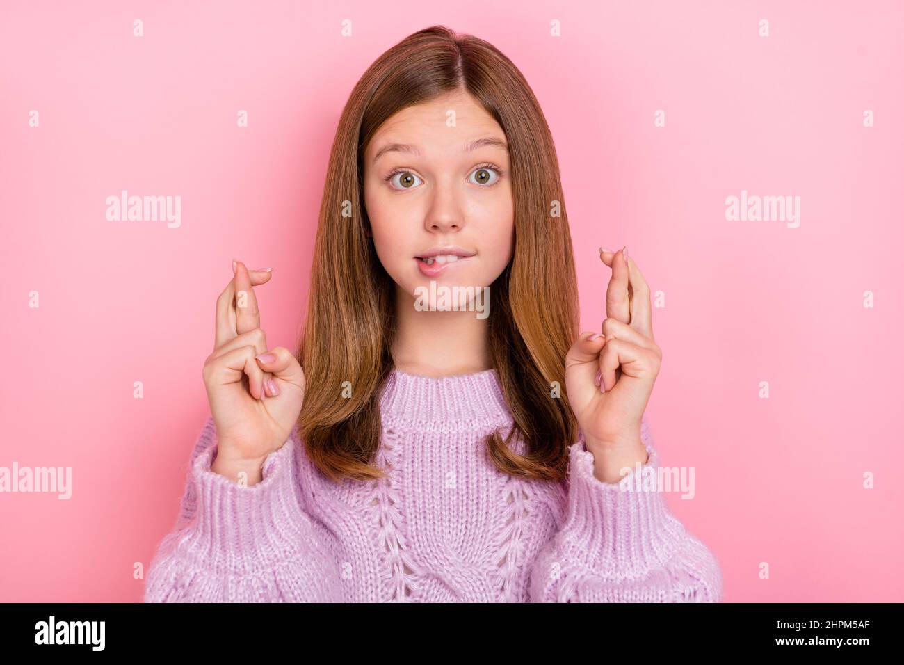 Foto von unsicher Mädchen gekleidet gestrickt Pullover Finger gekreuzt beißende Lippe isoliert rosa Farbe Hintergrund Stockfoto