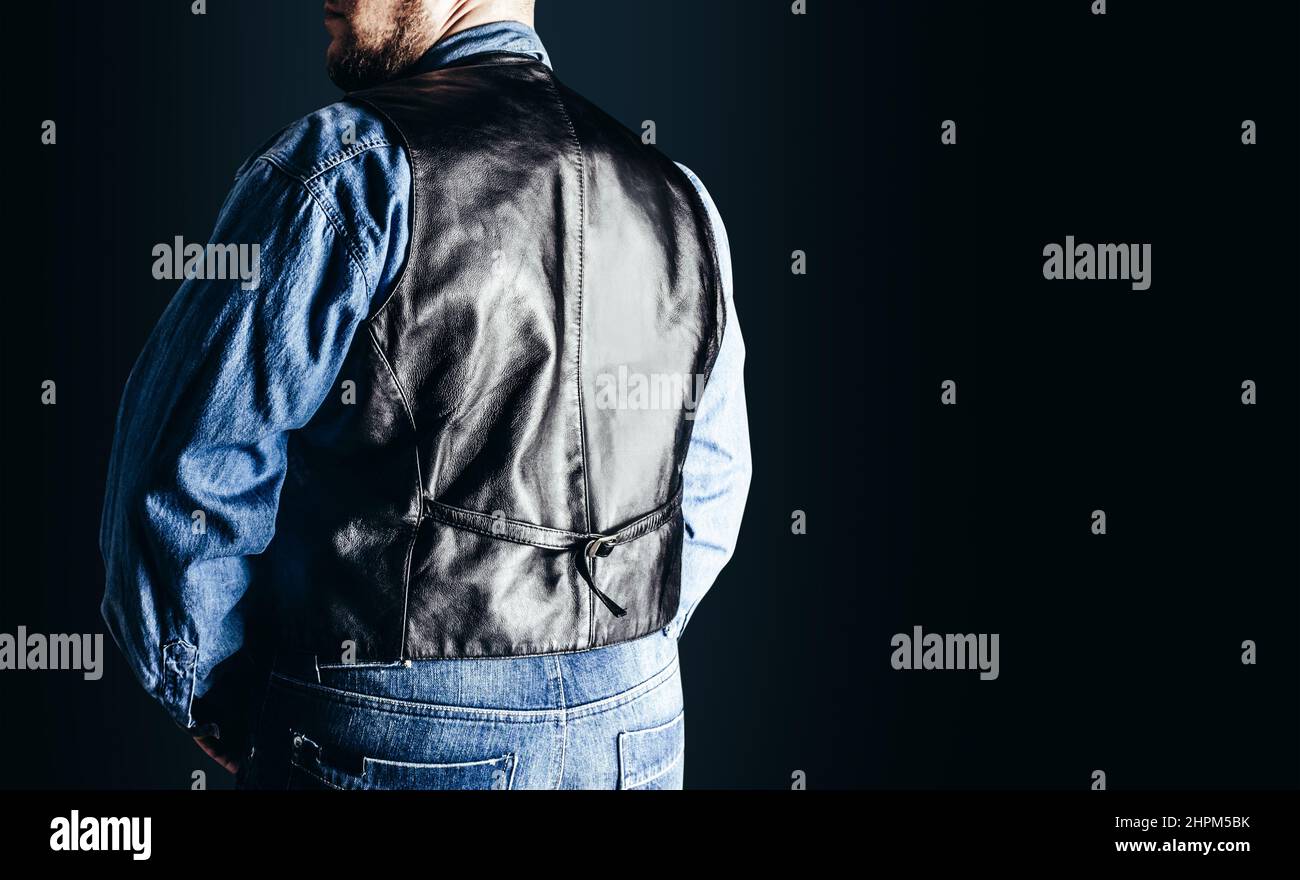 Rückansicht Foto von Mann in Jeans-Hemd und Leder Biker Weste auf dunkelblauem Hintergrund stehen. Stockfoto