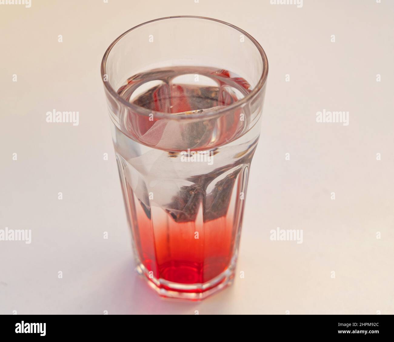 Eistee-Beutel, der sich in einem Glas klarem Wasser auflöst Stockfoto