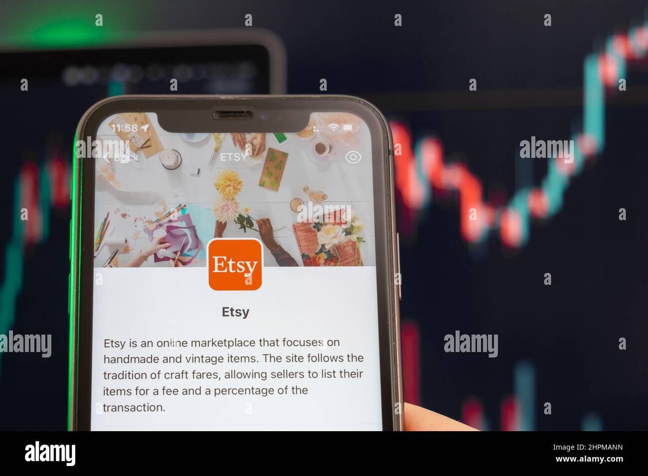 Der Aufwärtstrend der Aktienkursen von Etsy mit Grafiken im Hintergrund. Man hands Holding a Smartphone with Logo on the screen, February 2022, San Francisco, USA. Stockfoto
