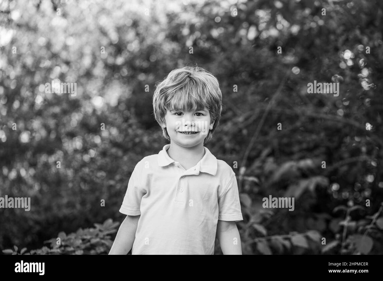 Kind im Freien in der Natur. Frohes Kind. Lustige Baby Junge auf einem Hintergrund von grünen Bäumen isoliert. Lächelnder Junge. Fröhliches, fröhliches Kind. Glücklich Stockfoto