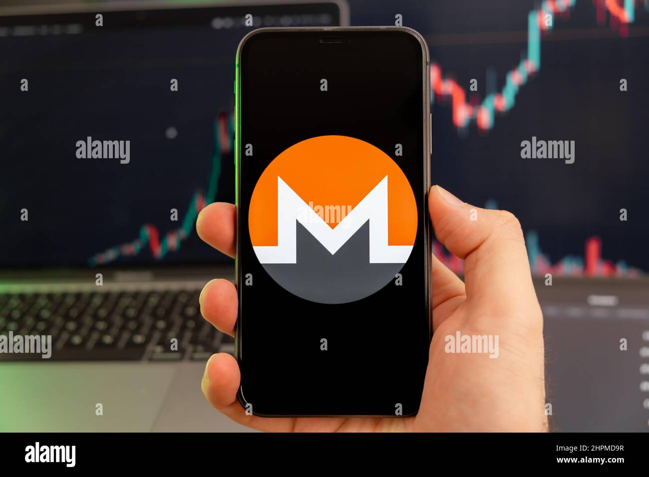 Monero XMR-App zur Analyse der Kryptowährung-Aktienmärkte auf dem Bildschirm von Mobiltelefonen in Menschenhand und wachsenden Charts, die im Hintergrund Handelsdaten enthalten, Februar 2022, San Francisco, USA. Stockfoto