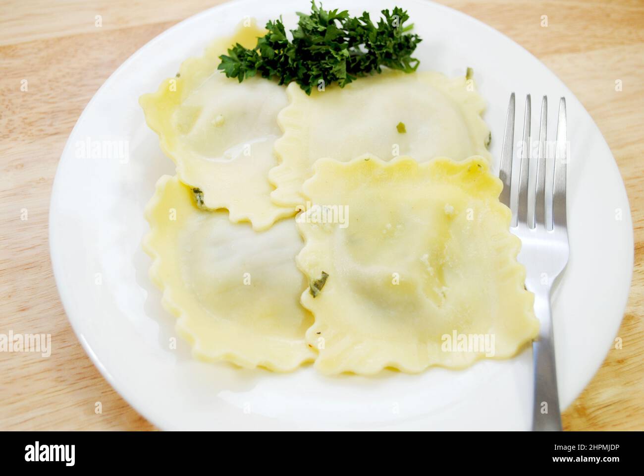Vier appetitlich große Spinat Raviolis auf einem weißen mit Petersilie Garnish Stockfoto