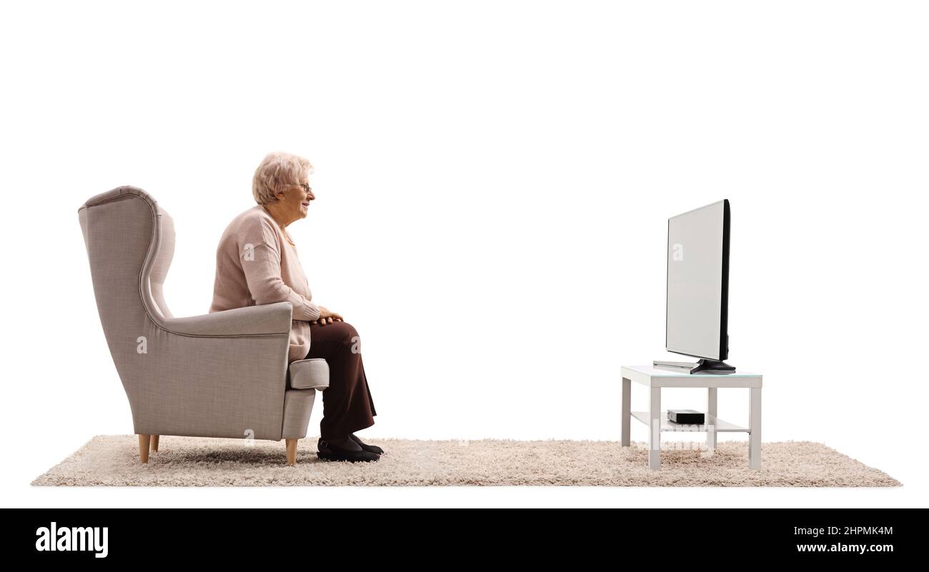 Profilaufnahme einer älteren Frau, die in einem Sessel sitzt und isoliert auf weißem Hintergrund Fernsehen sieht Stockfoto