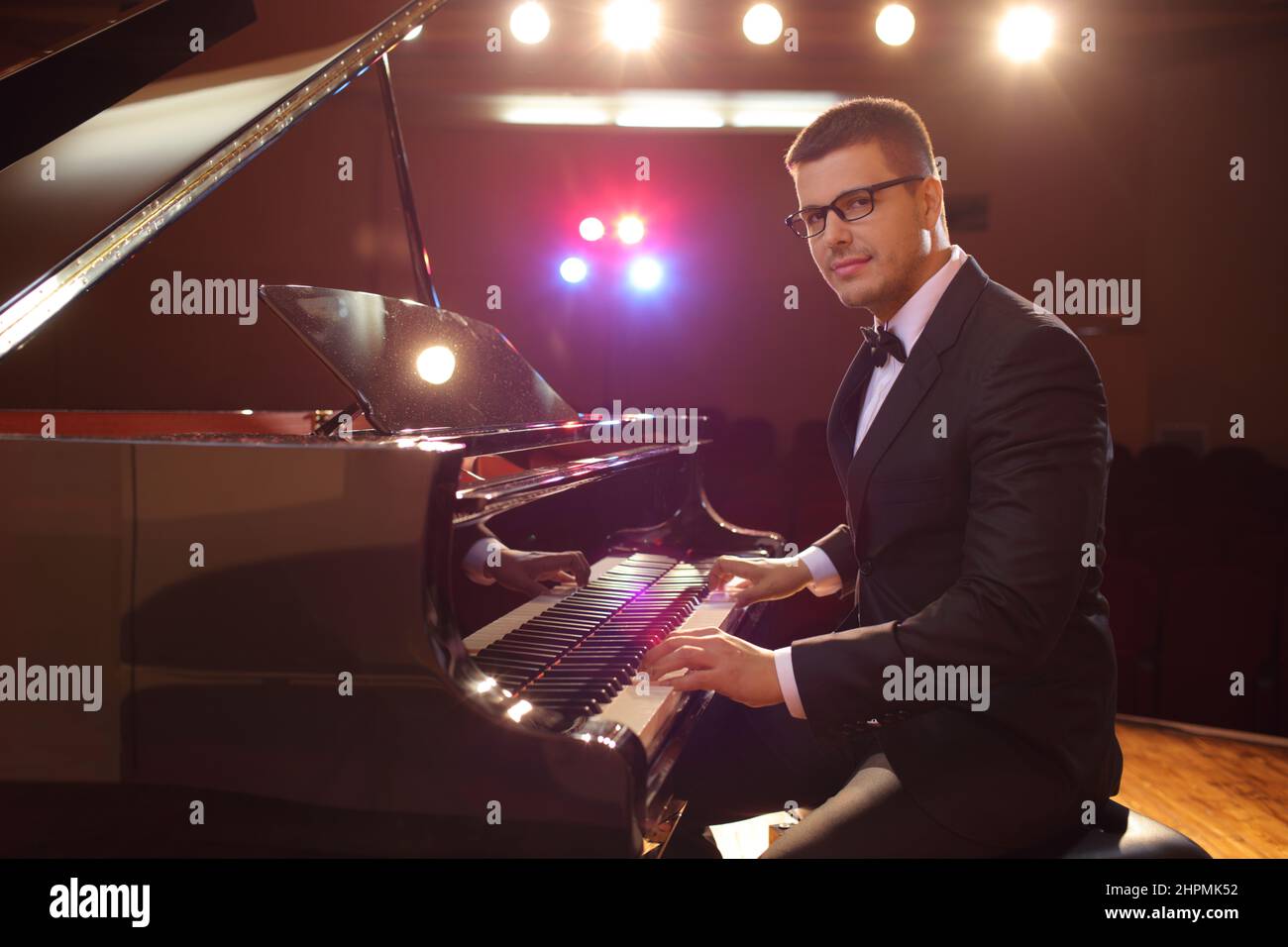 Junger, hübscher Pianist auf der Bühne, der die Kamera anschaut Stockfoto