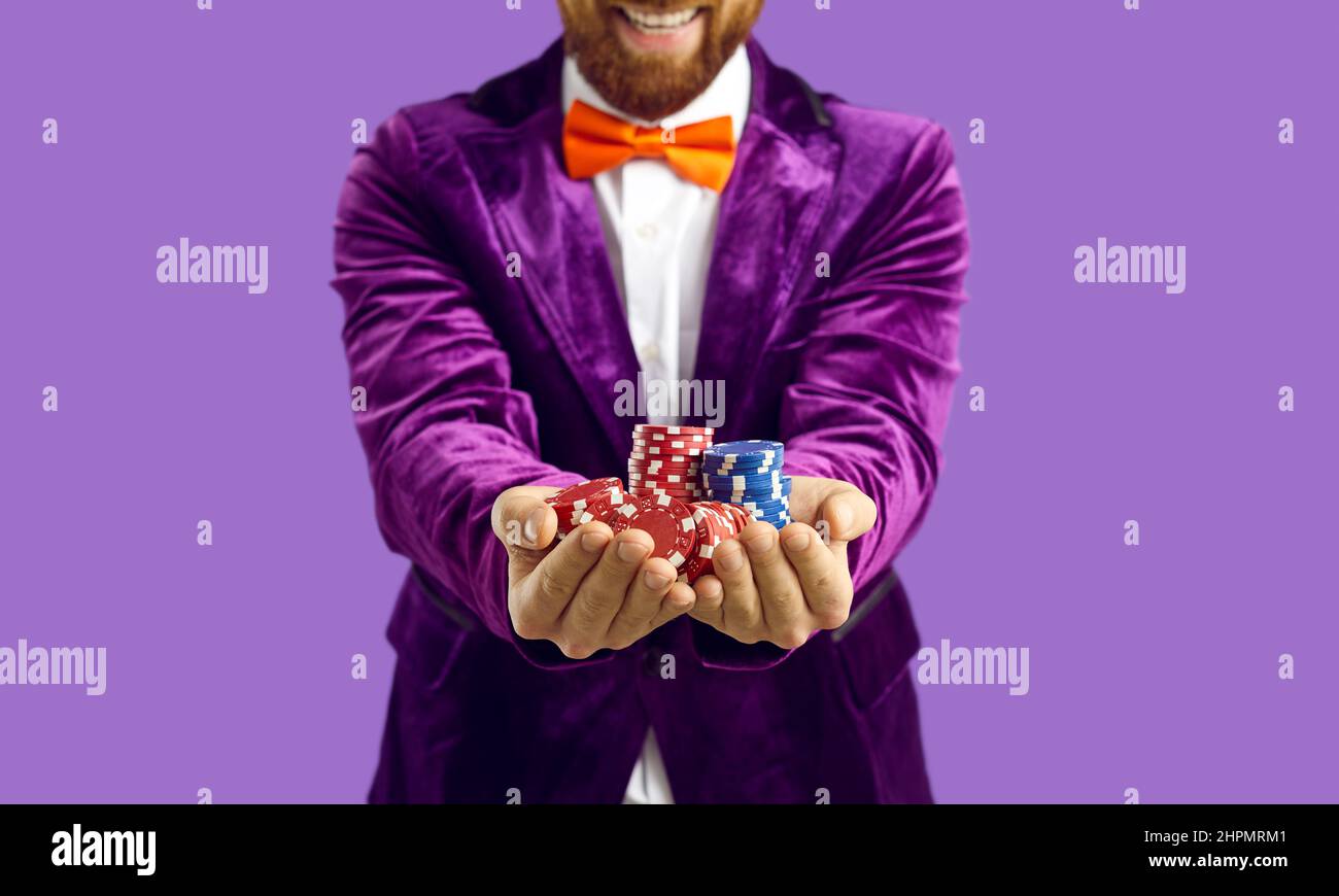 Nahaufnahme von Poker-Chips in den Händen von freudig aufgeregt Mann auf lila Hintergrund isoliert. Stockfoto