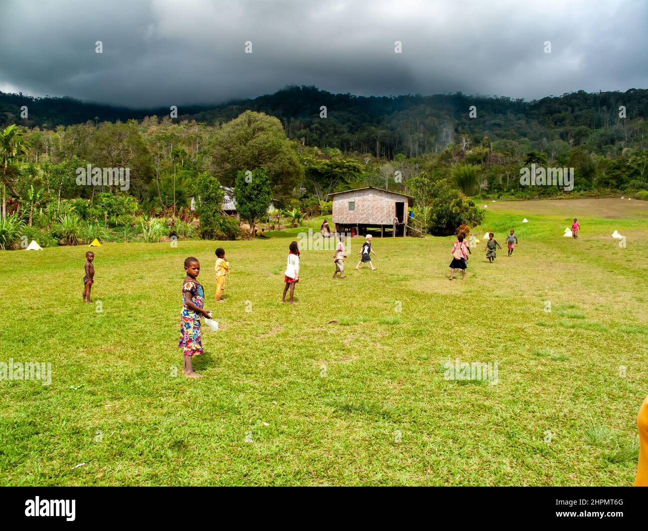 Kleine Kinder spielen Fußball in der Eastern Highlands Province of PNG, in großer Höhe im Kaffeeanbaugebiet, Bergregenwald im Hintergrund Stockfoto