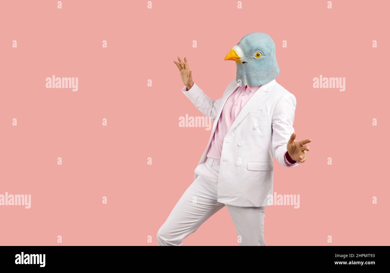 Lustiger Mann in einer seltsamen Taubenmaske, tanzt und hat Spaß auf einer verrückten Party mit ausgefallenen Kleidern Stockfoto