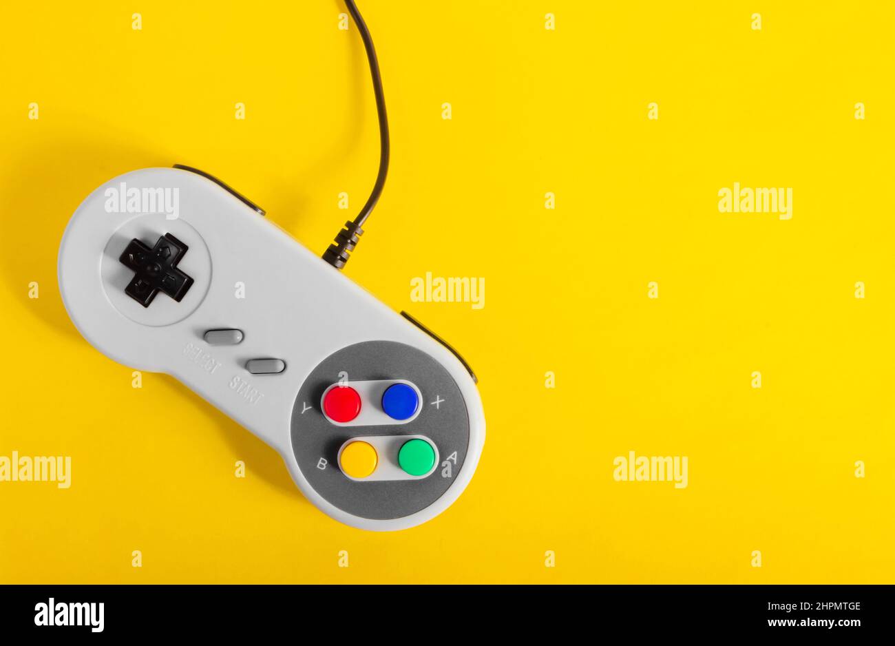 Foto des klassischen grauen 8 Bit Game Pad Controller auf gelbem Hintergrund. Stockfoto