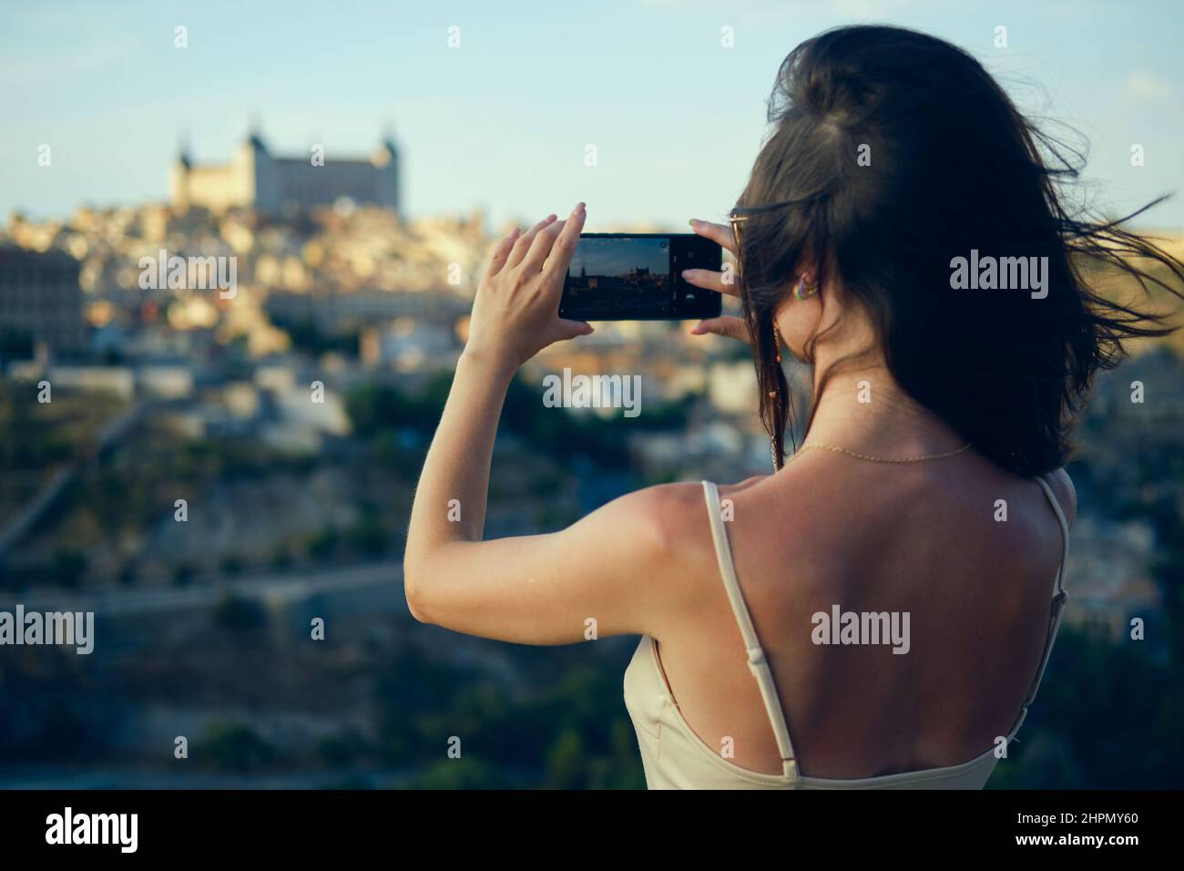 Rückansicht junge Frau Handy halten Foto machen Genießen Sie die Stadtansicht von Toledo von der Smartphone-Kamera aus. Touristen fangen Moment, Fotografieren berühmt Stockfoto