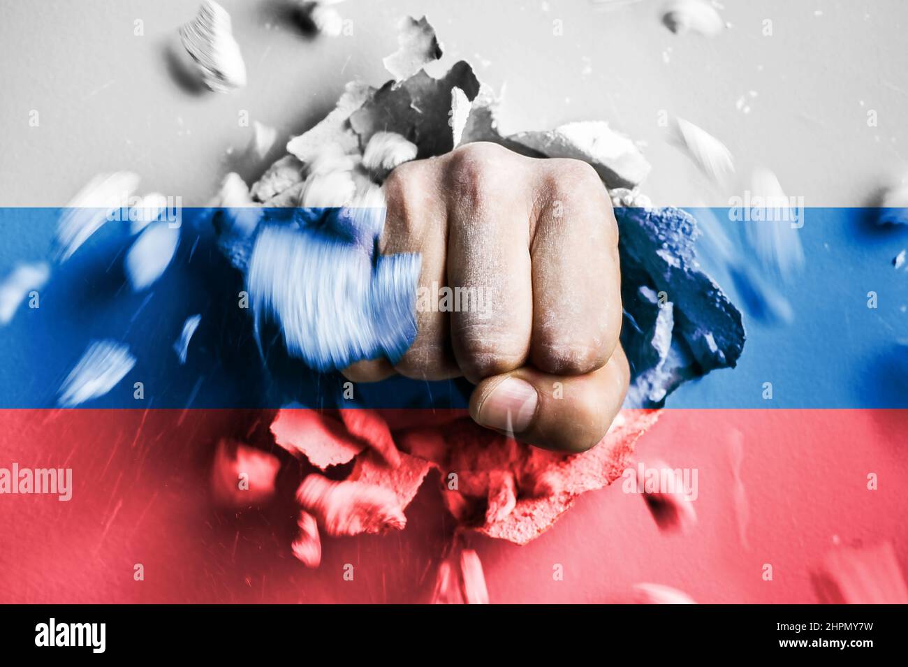 Eine Faust stanzt durch eine Betonwand mit den Farben der russischen Nationalflagge. Das Konzept der russischen Kriegsangriffs Stockfoto