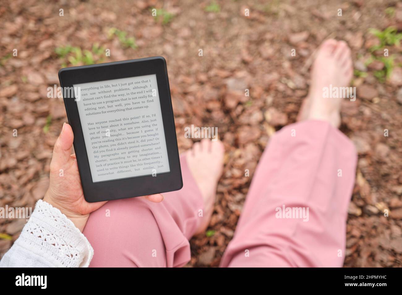Unerkennbare reife Frau, die ein eBook auf einem elektronischen Leser liest, der in einem Park sitzt. Konzepte: Technologie und Lesen. Stockfoto