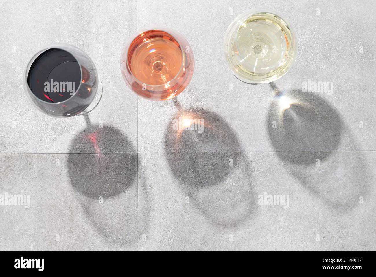 Rot-, Weiß- und Roséwein in Weingläsern isoliert auf Beton-Hintergrund mit Kopierraum. Draufsicht. Stockfoto