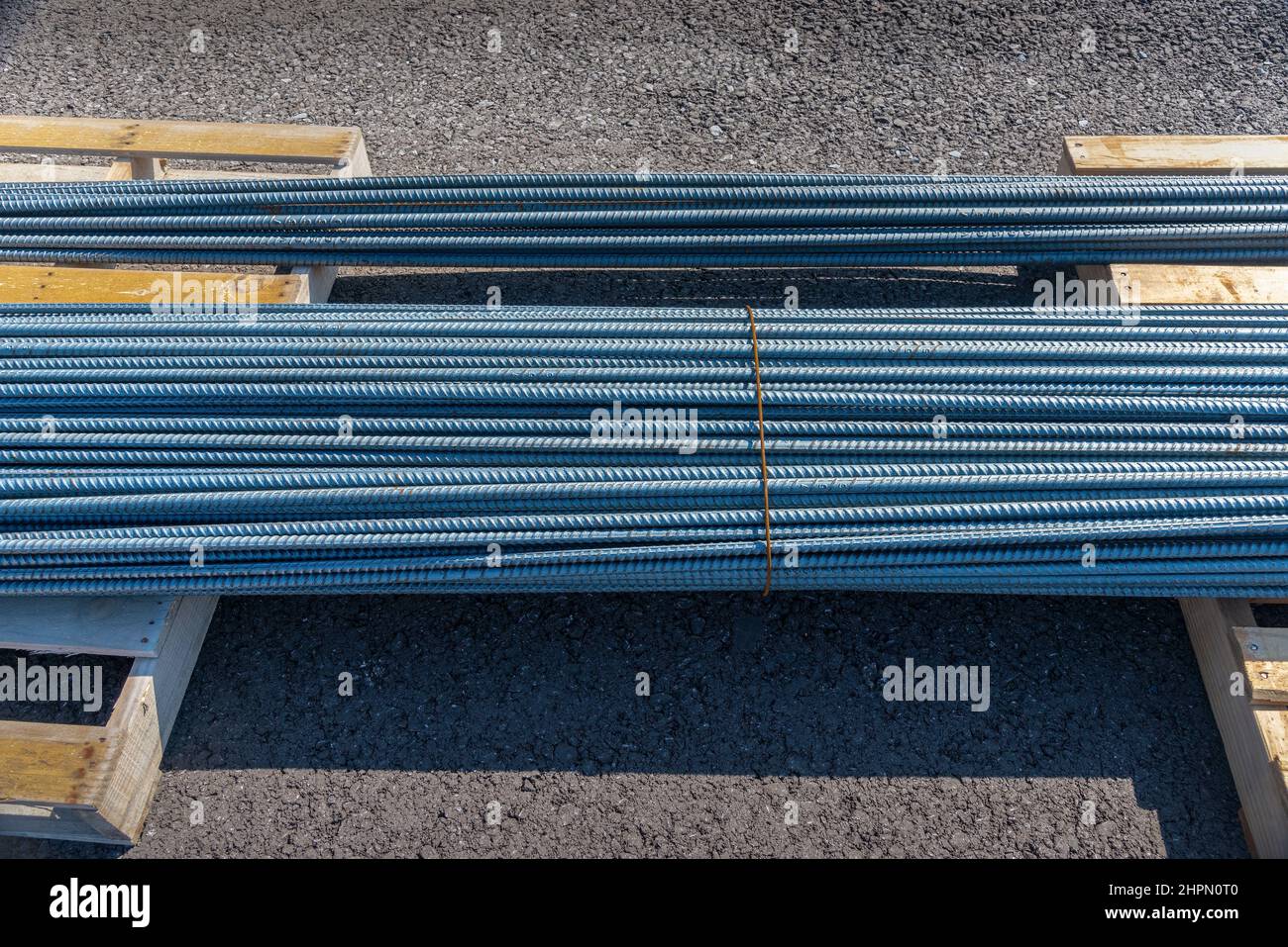 Horizontaler Schuss von zwei Stahlstapeln auf Holzpaletten auf einer neuen kommerziellen Baustelle. Stockfoto