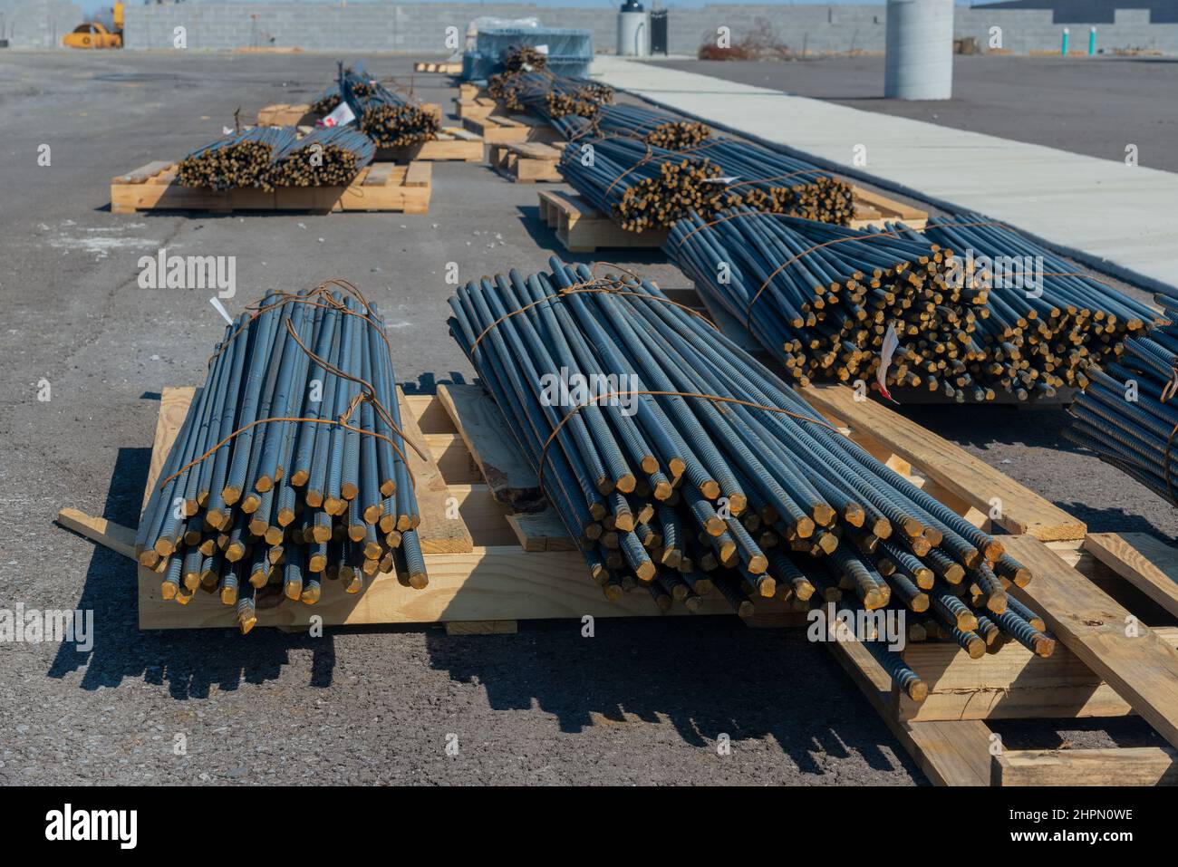 Horizontale Aufnahme von Stahlstapeln auf Holzpaletten auf einer neuen Industriebaustelle. Stockfoto