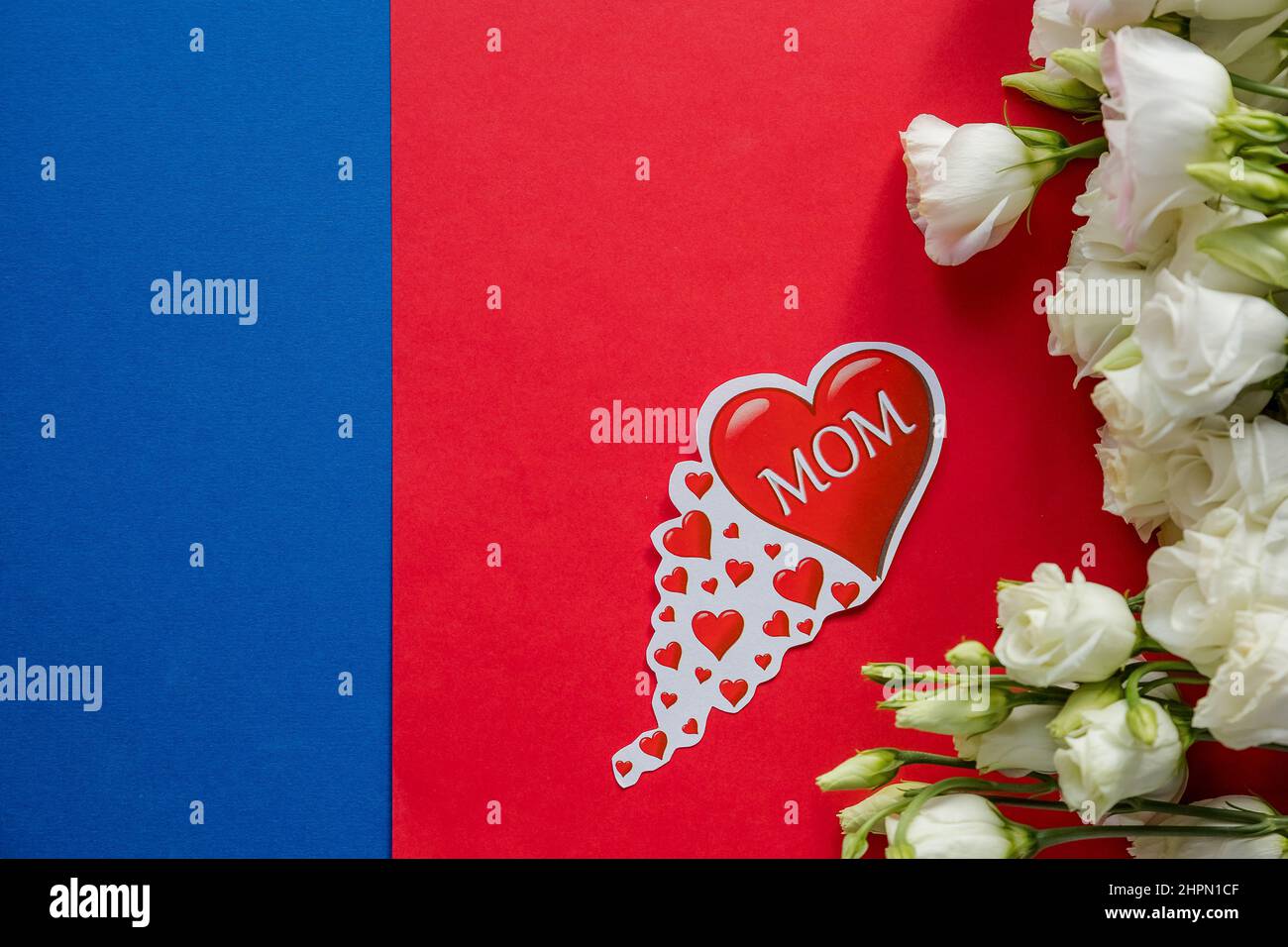 Happy Mother's Day Grußkarte mit Frühlingsblumen und dekorativem Herz auf rot-blauem Hintergrund.Design-Konzept - Draufsicht auf Strauß schön Stockfoto