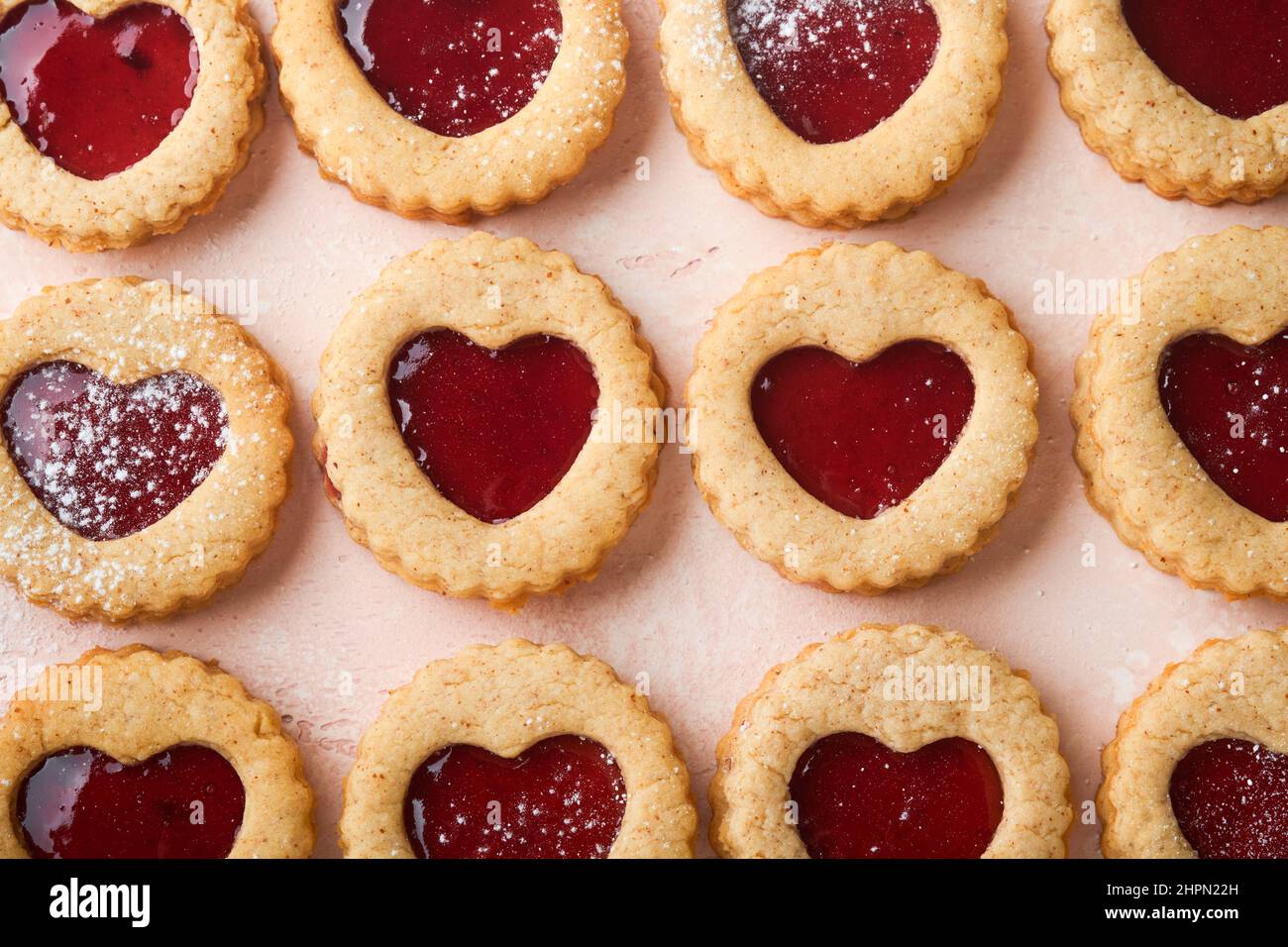 Traditioneller Linzer-Keks mit Erdbeermarmelade und Puderzucker auf rosa schönem Hintergrund. Draufsicht. Traditionelles hausgemachtes österreichisches Süßes Dessert Foo Stockfoto