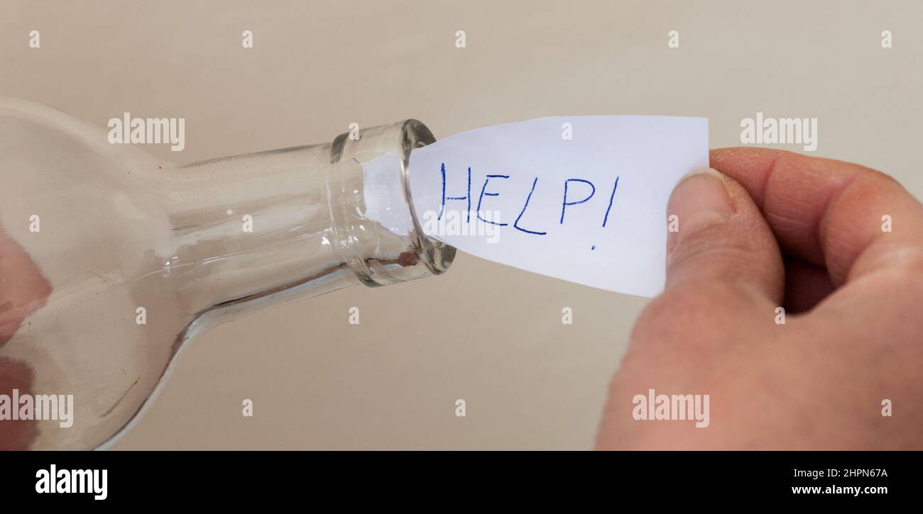 Die Hände einer Frau legen eine Hilfsbotschaft in eine Flasche Stockfoto